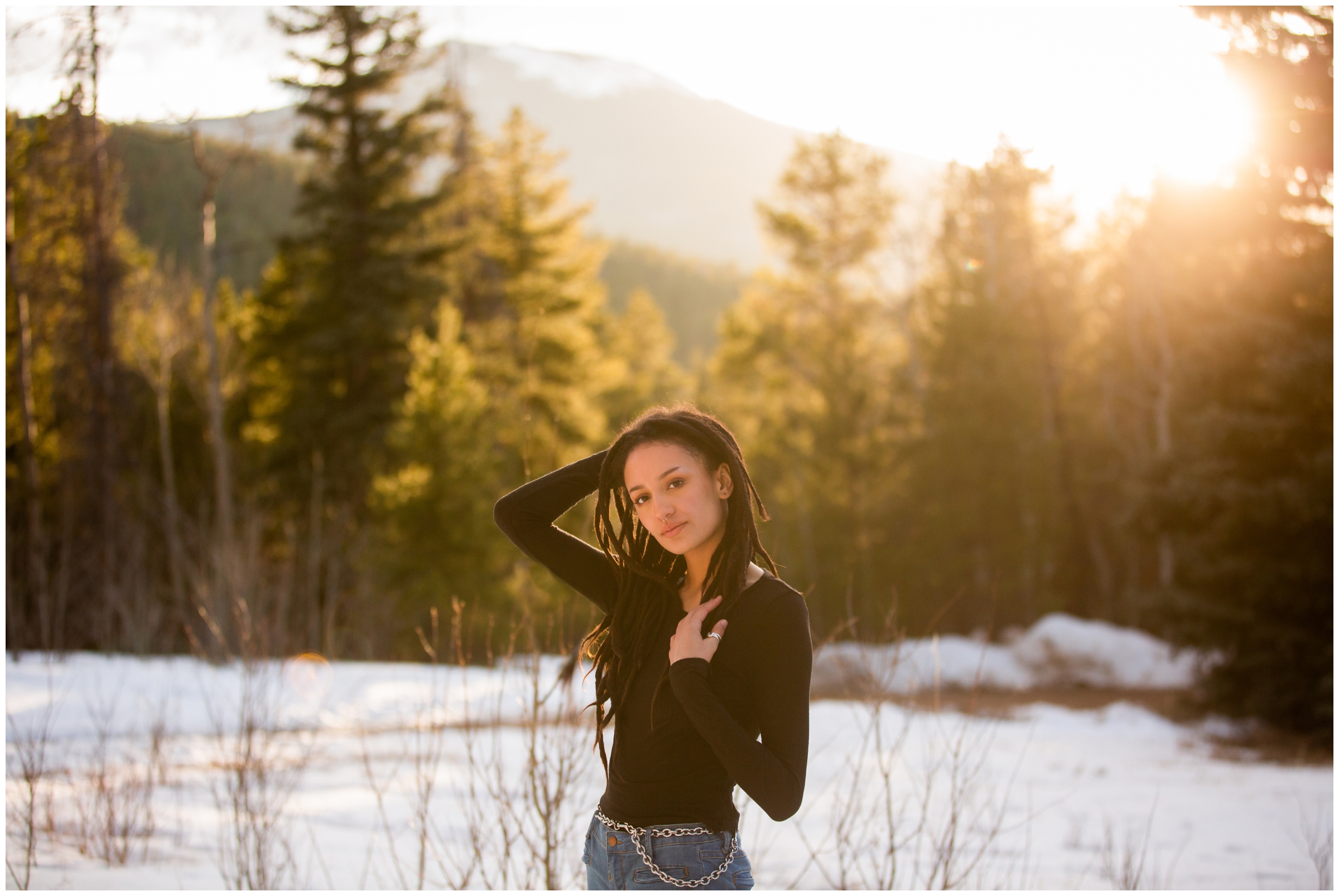 Teen posing in the snow with mountains in background during spring graduation portraits in CO