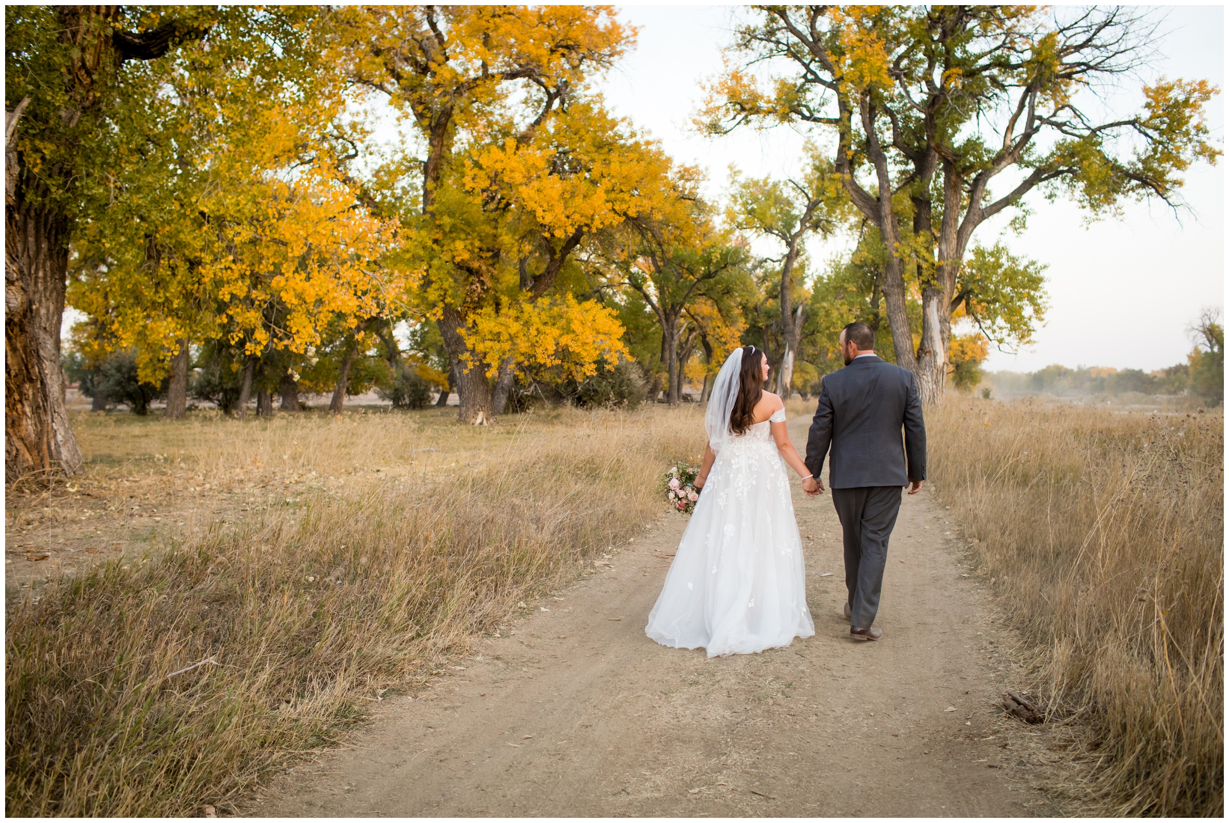 couple walking down dirt road during rustic backyard wedding photos in Platteville Colorado 