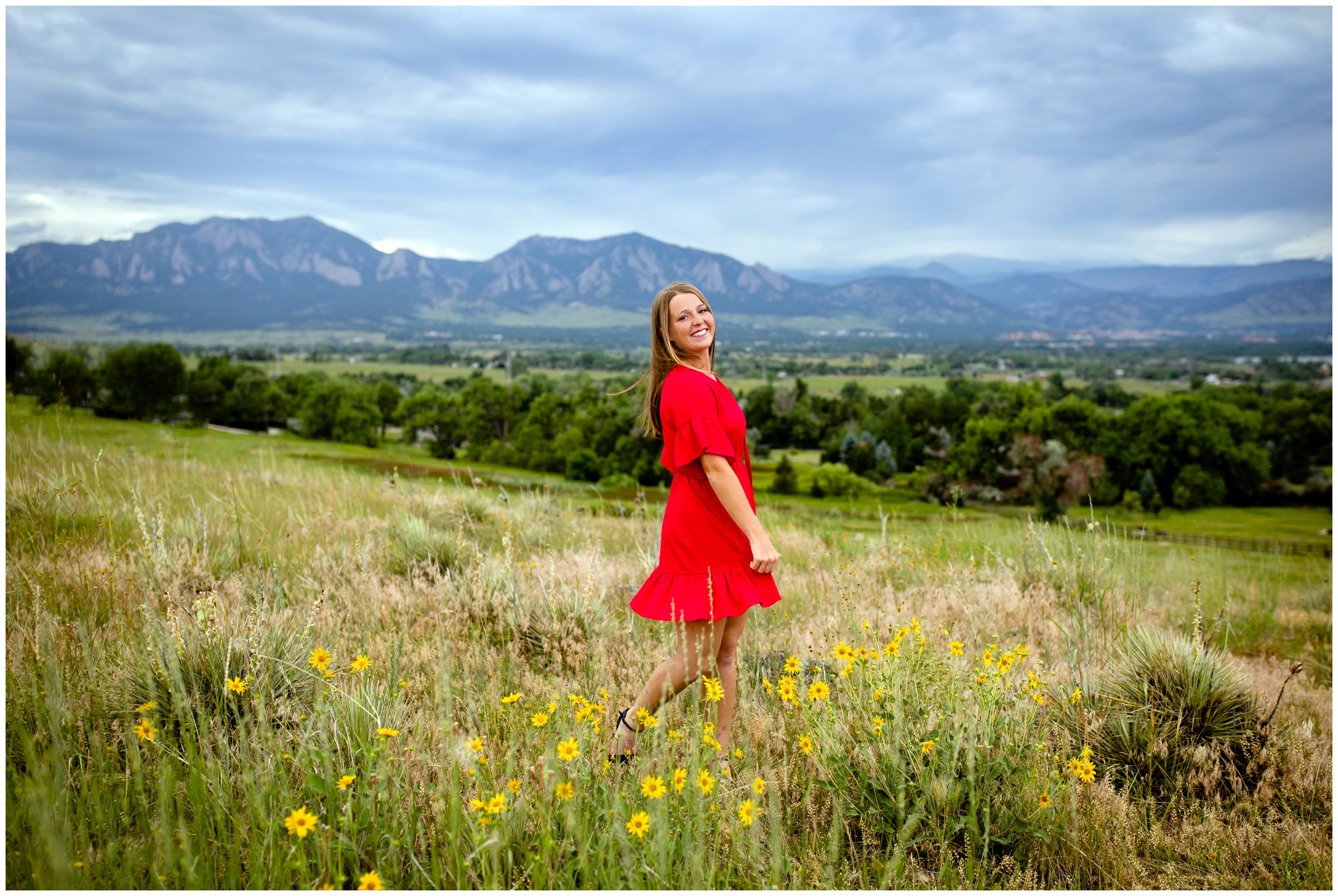teen girl in red dress twirling in a field during Boulder flatirons senior photos at Davidson Mesa 