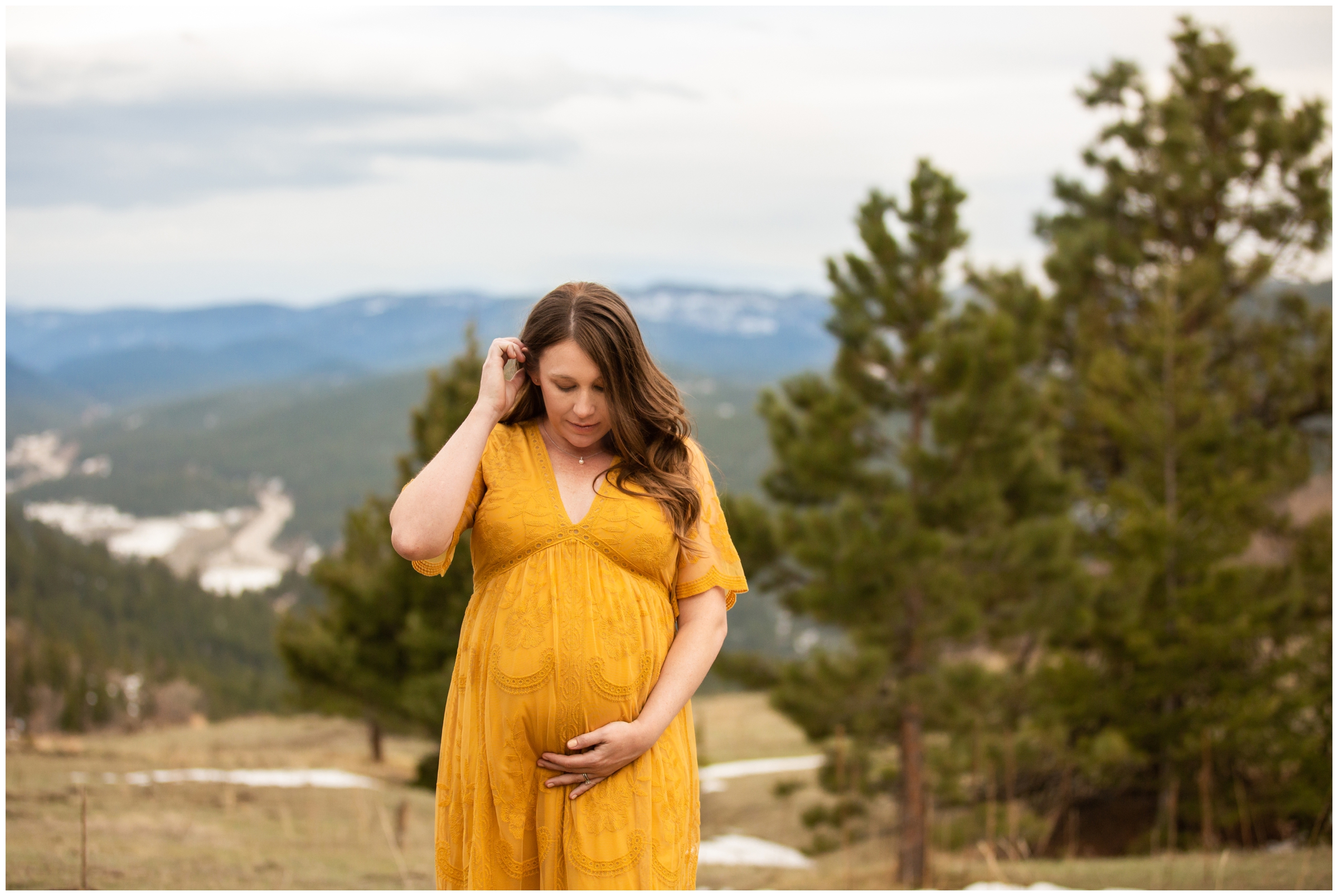 woman in mustard yellow maternity dress posing for pregnancy photo session in Colorado mountains