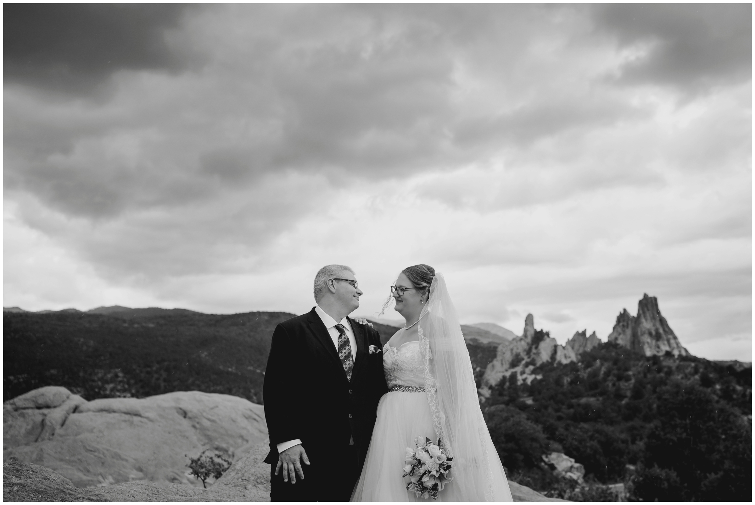 couple posing at High Point Overlook with mountains and red rock formations during Garden of the Gods summer wedding 