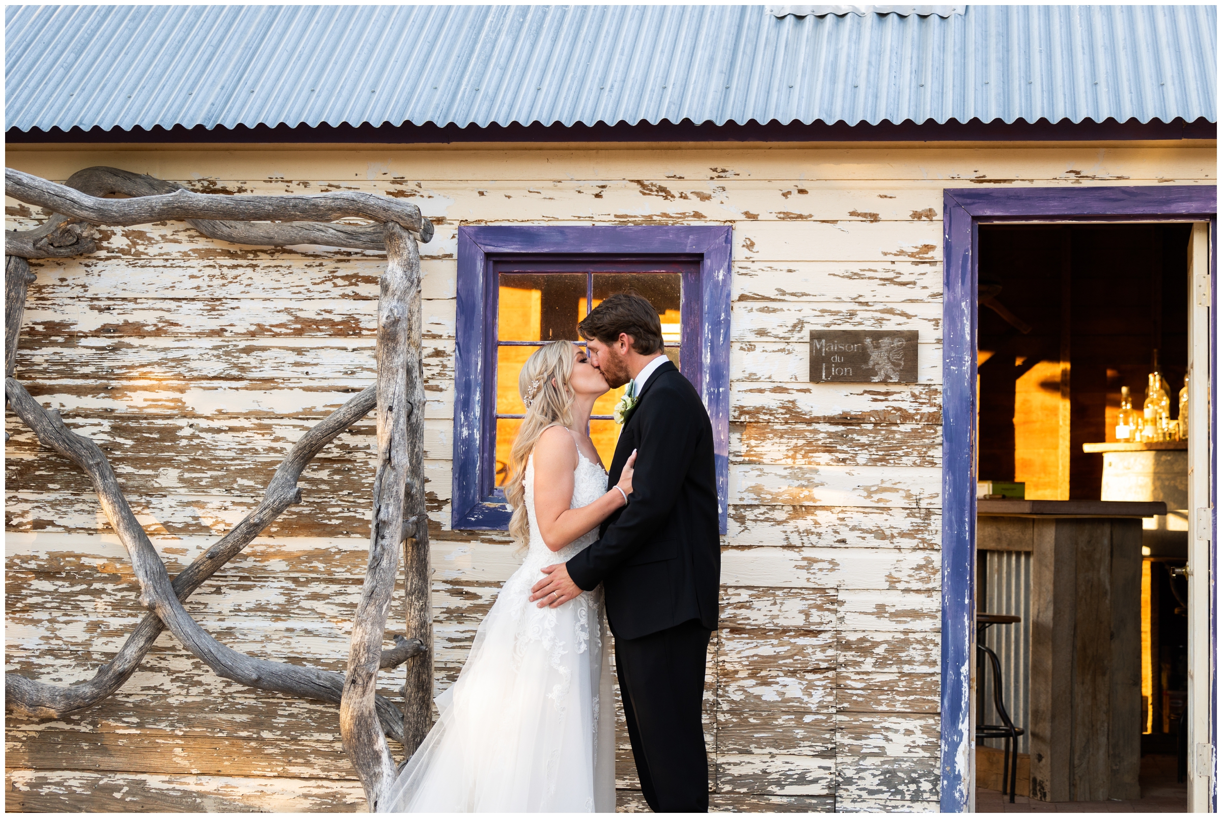 couple kissing in front of rustic wooden building during Lionscrest Manor wedding pictures