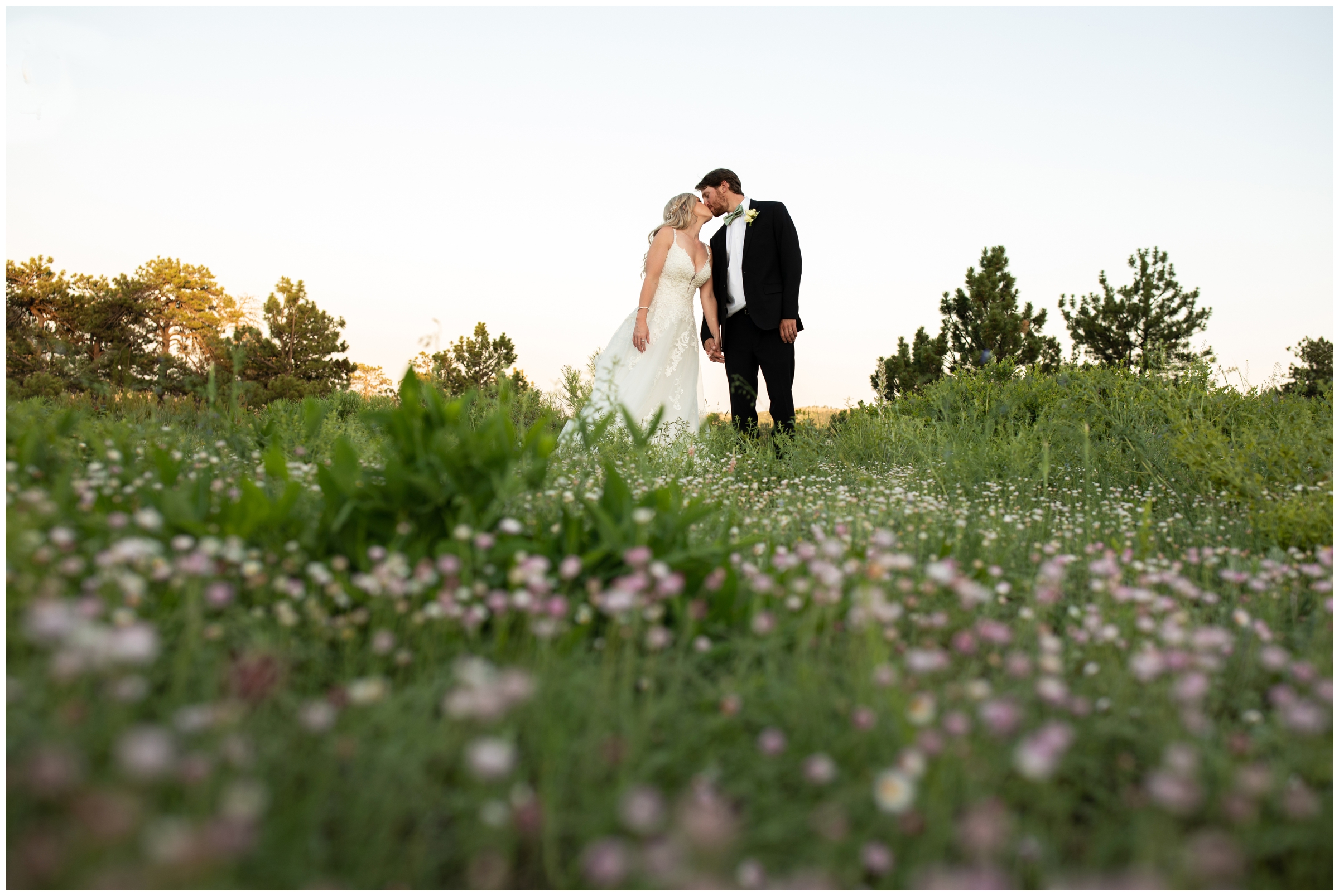bride and groom kissing in field of wildflowers during Colorado mountain wedding photos 