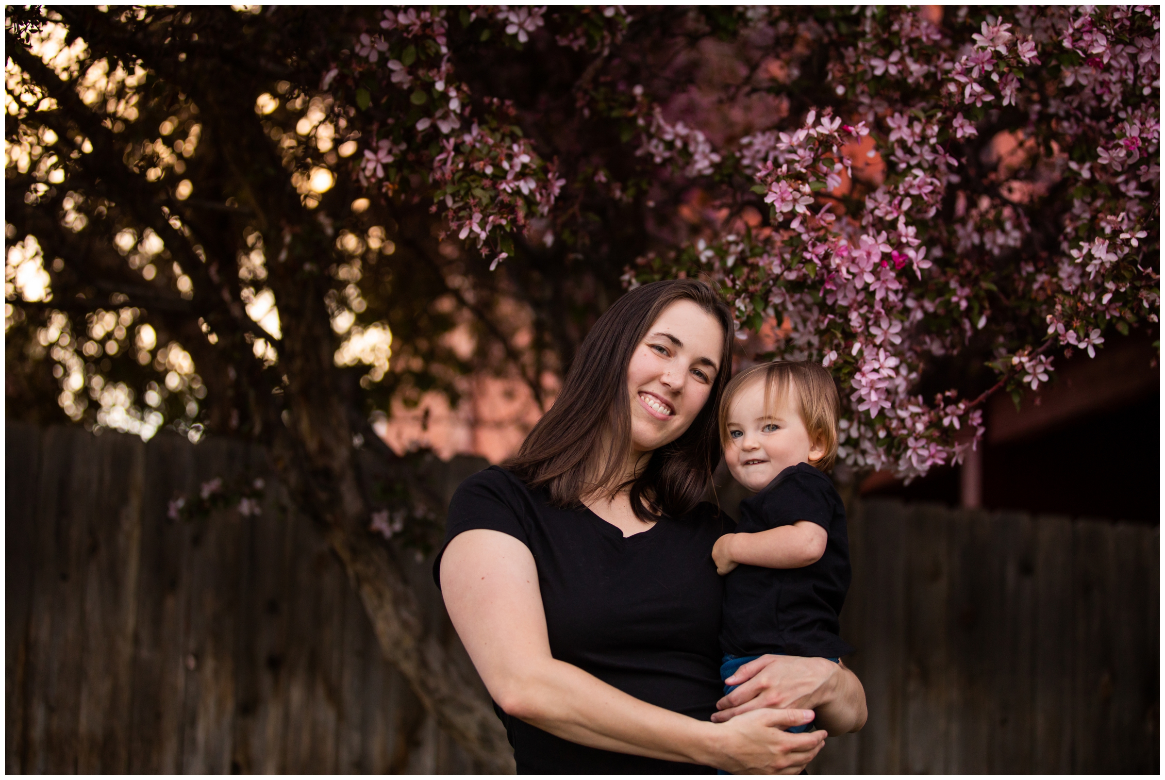 mom holding daughter during spring family portraits with blossoming trees in Colorado 