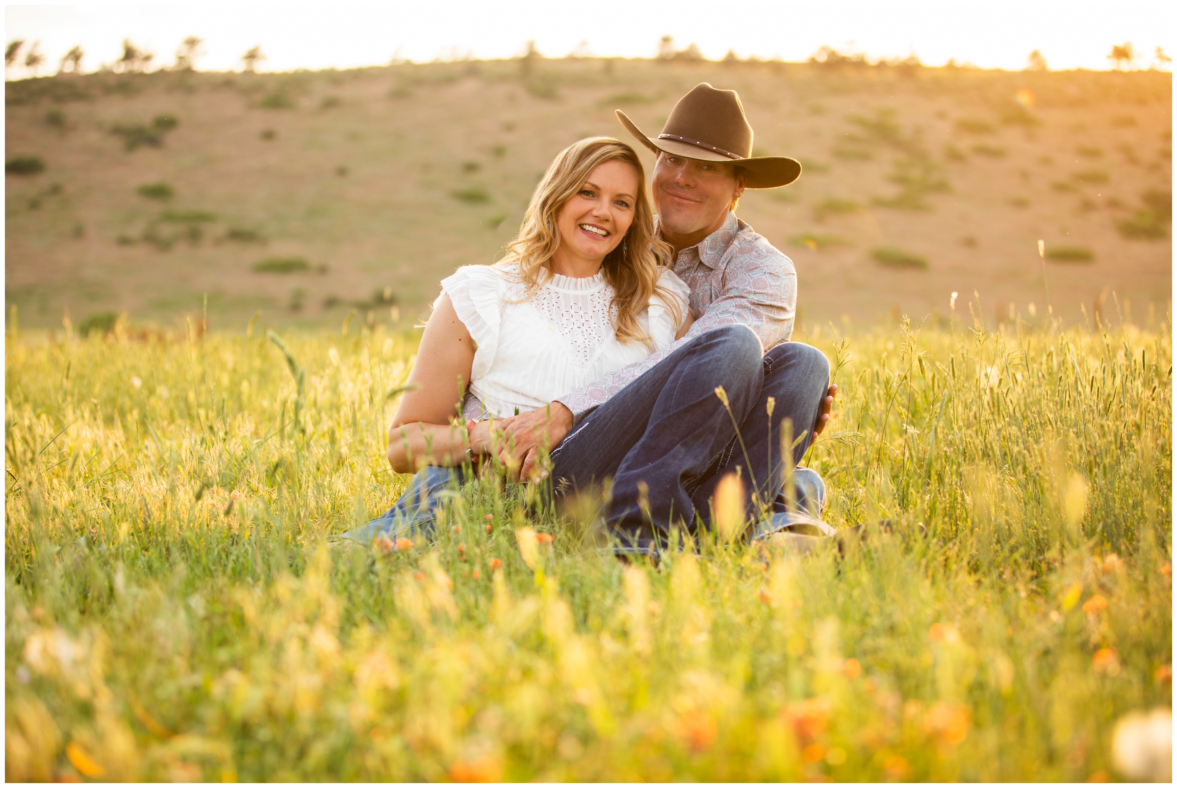 couple sitting in a field of wildflowers during Loveland engagement portraits at sunny golden hour 