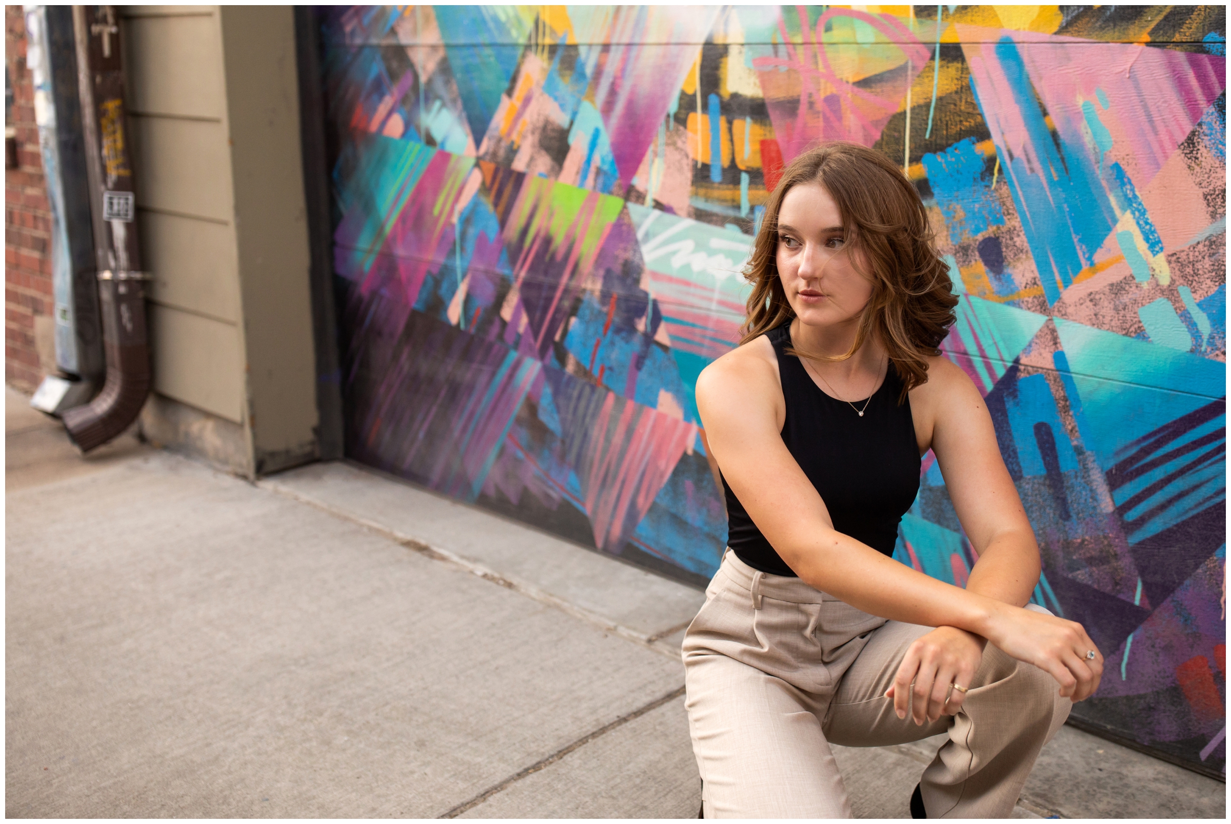 Teen posing in front of colorful wall mural during Colorado high school graduation photography session 