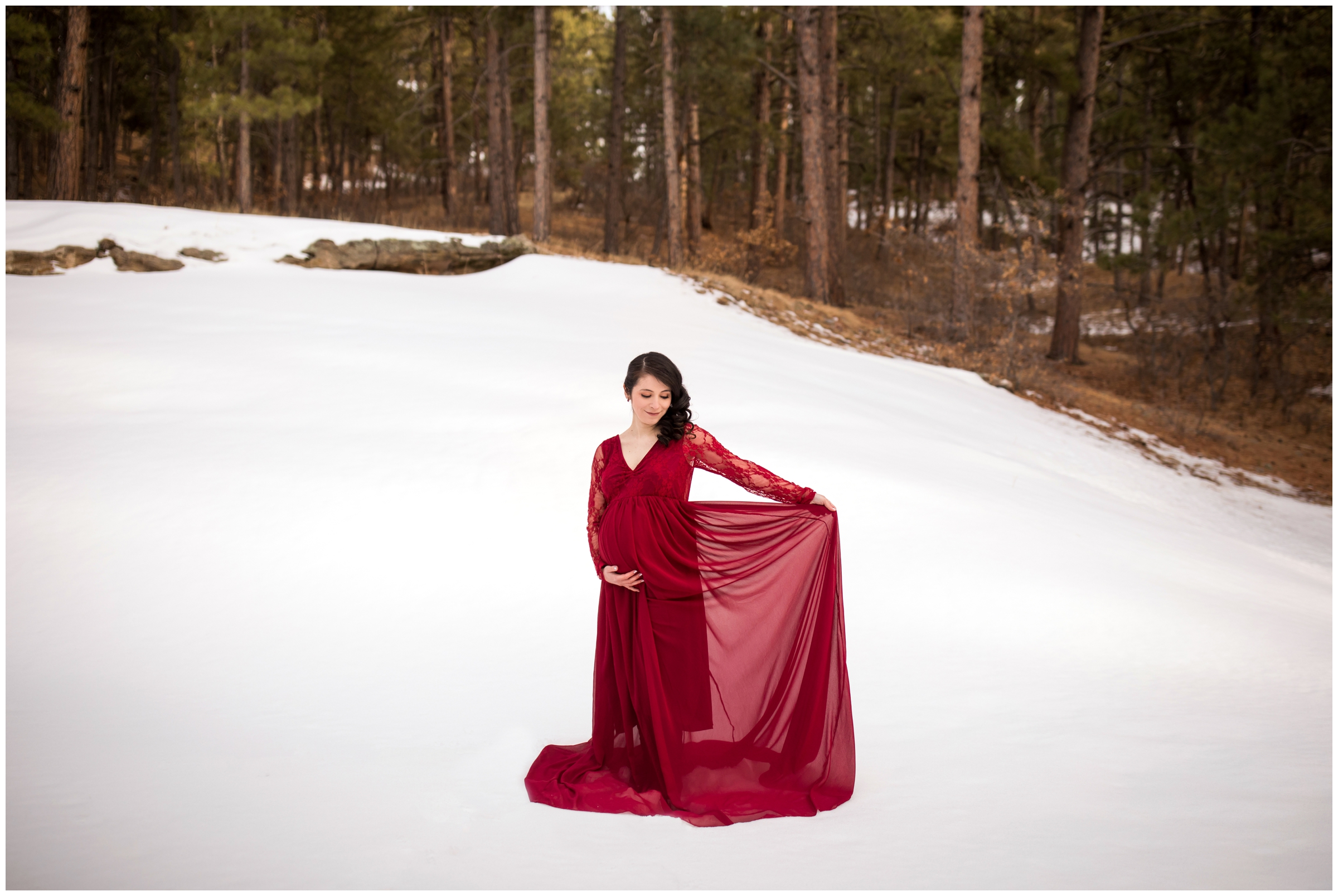 woman in red dress posing in the snow during Colorado winter maternity portraits 