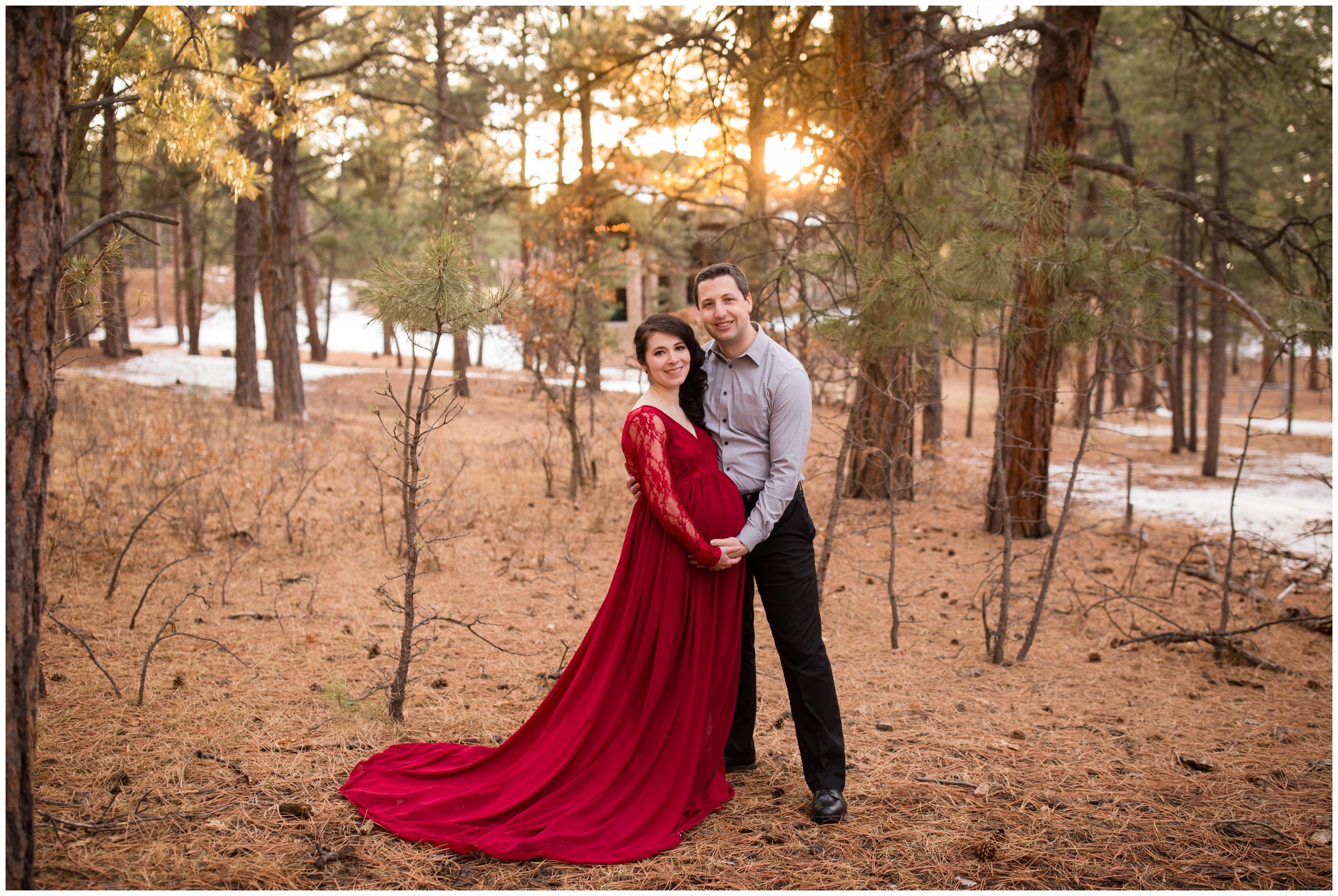 couple posing for maternity portraits in a Colorado forest during winter
