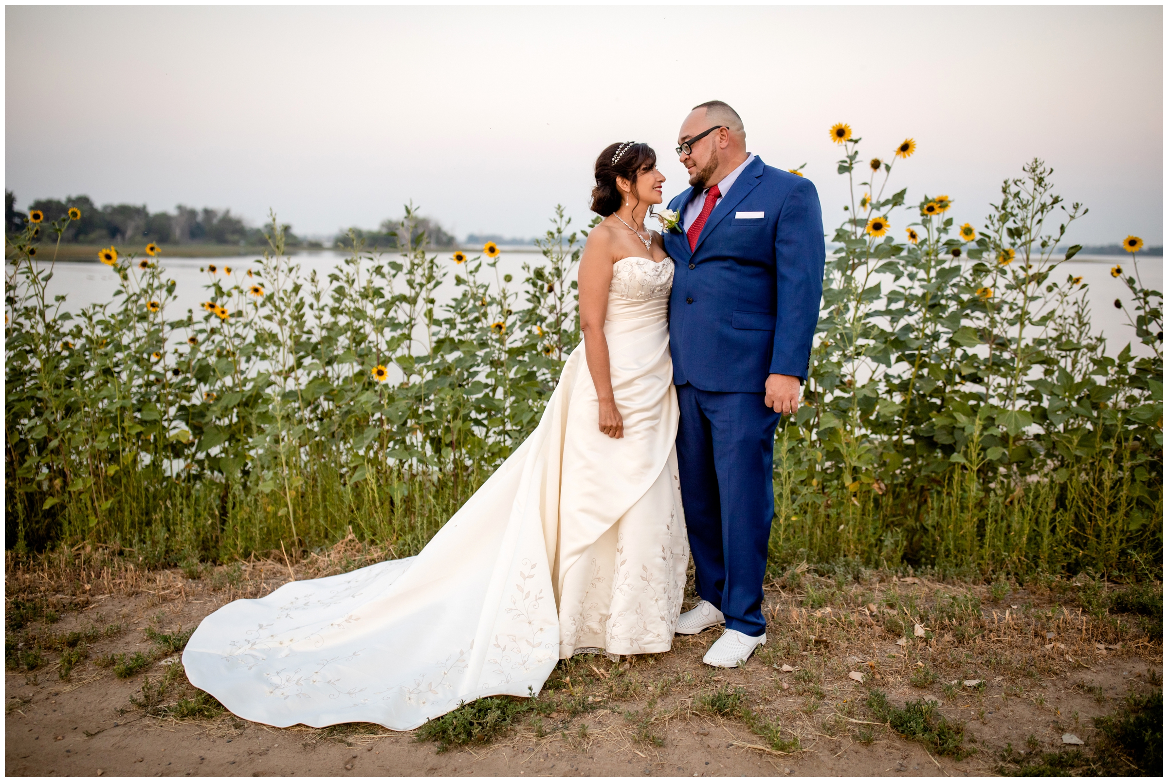 couple posing by small sunflowers during Colorado lake wedding portraits in Brighton 