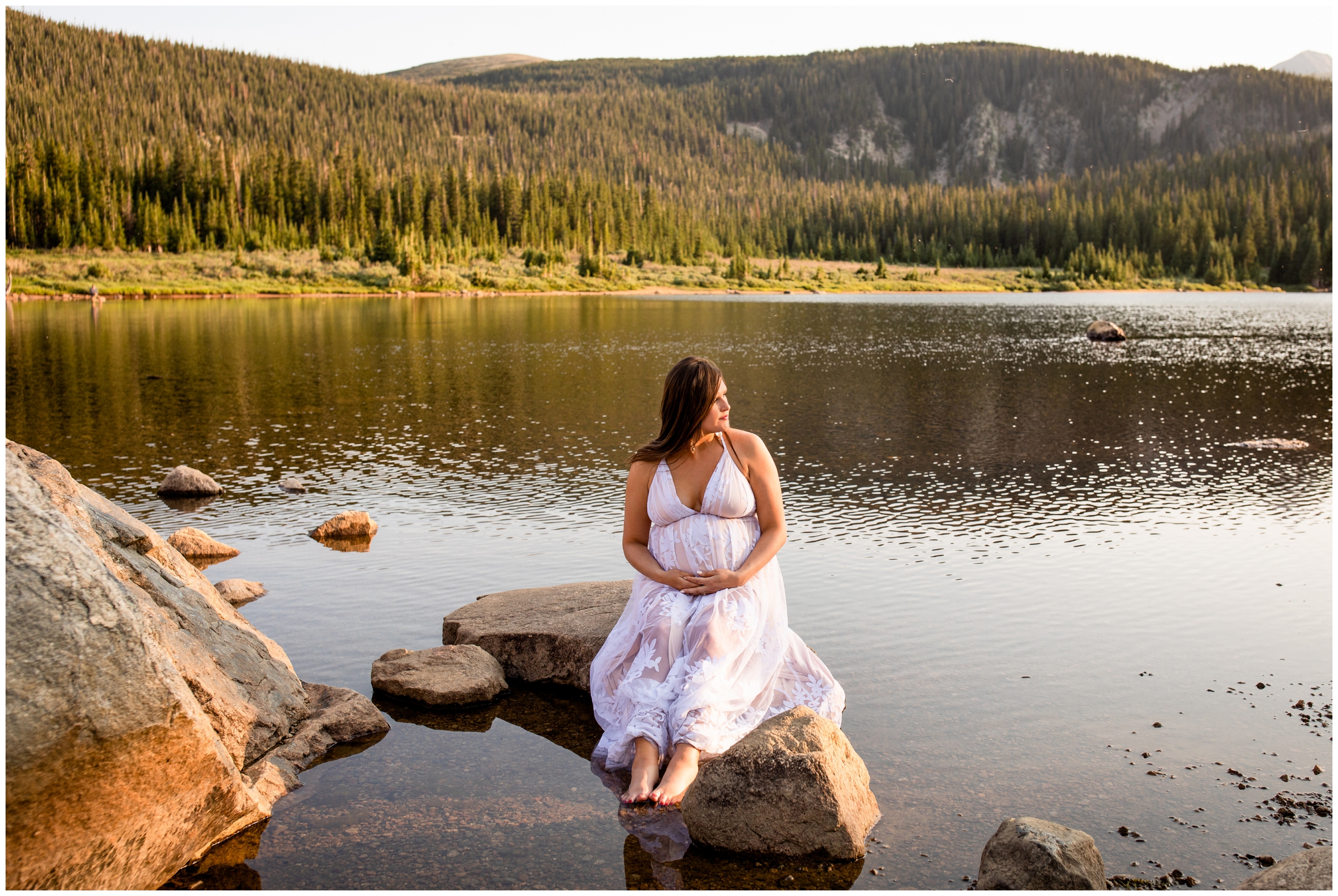 pregnant woman dipping toes into water at Colorado mountain maternity photo session at Brainard lake 
