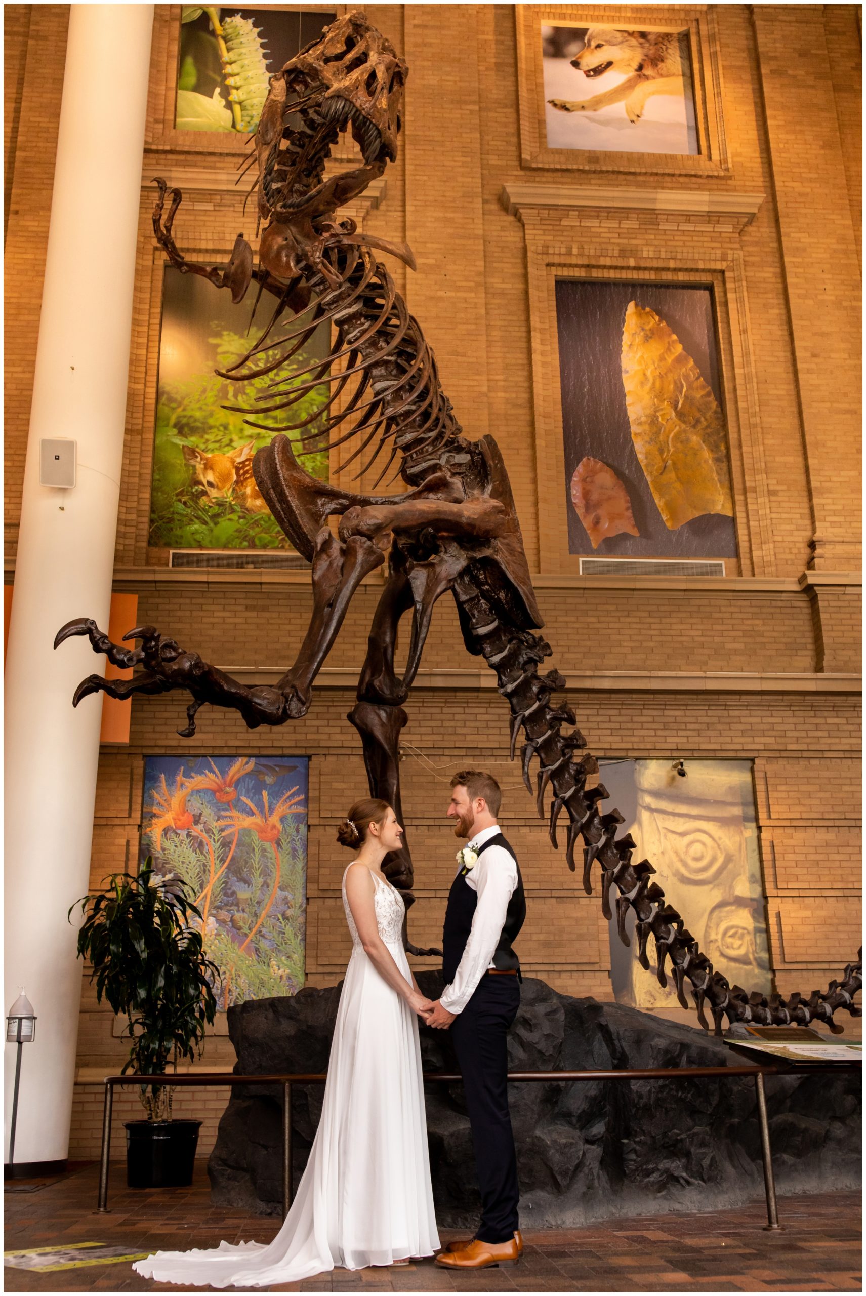bride and groom posing with t-rex dinosaur bones at Denver Colorado museum wedding 