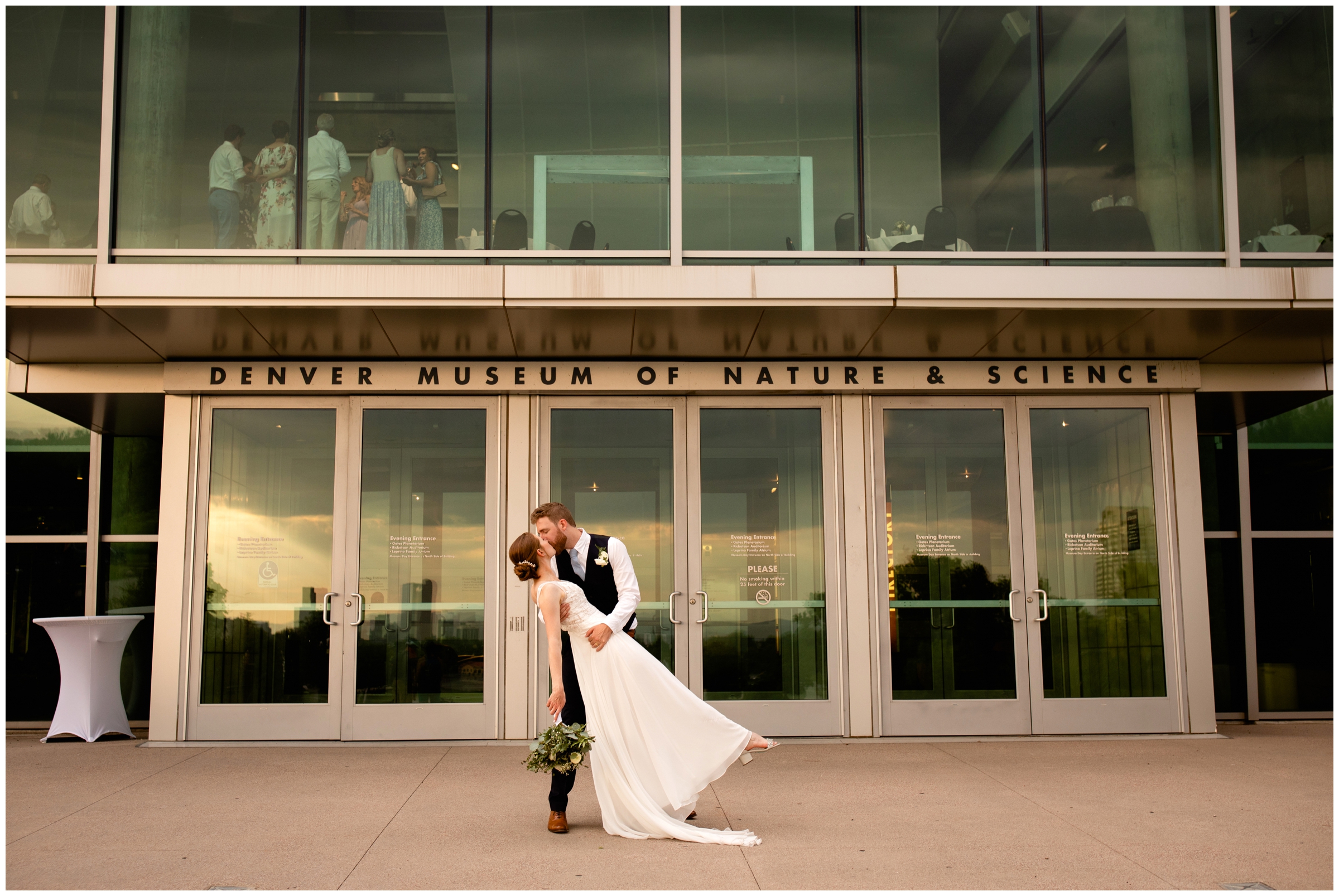 groom dipping bride in front of Denver museum of Nature in Science during Colorado summer wedding 