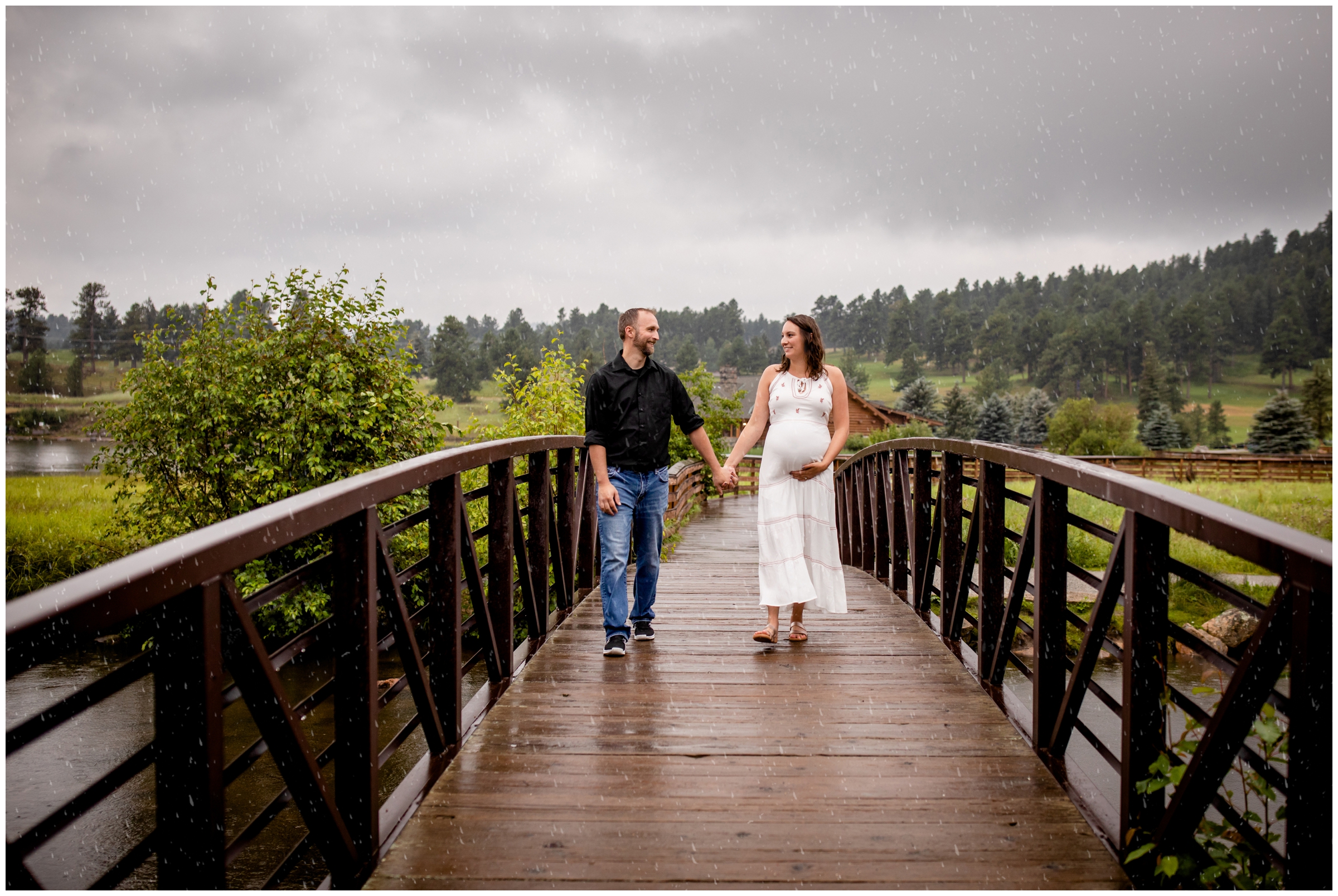 couple walking on bridge in the rain during Colorado mountain maternity pictures at Evergreen Lake House