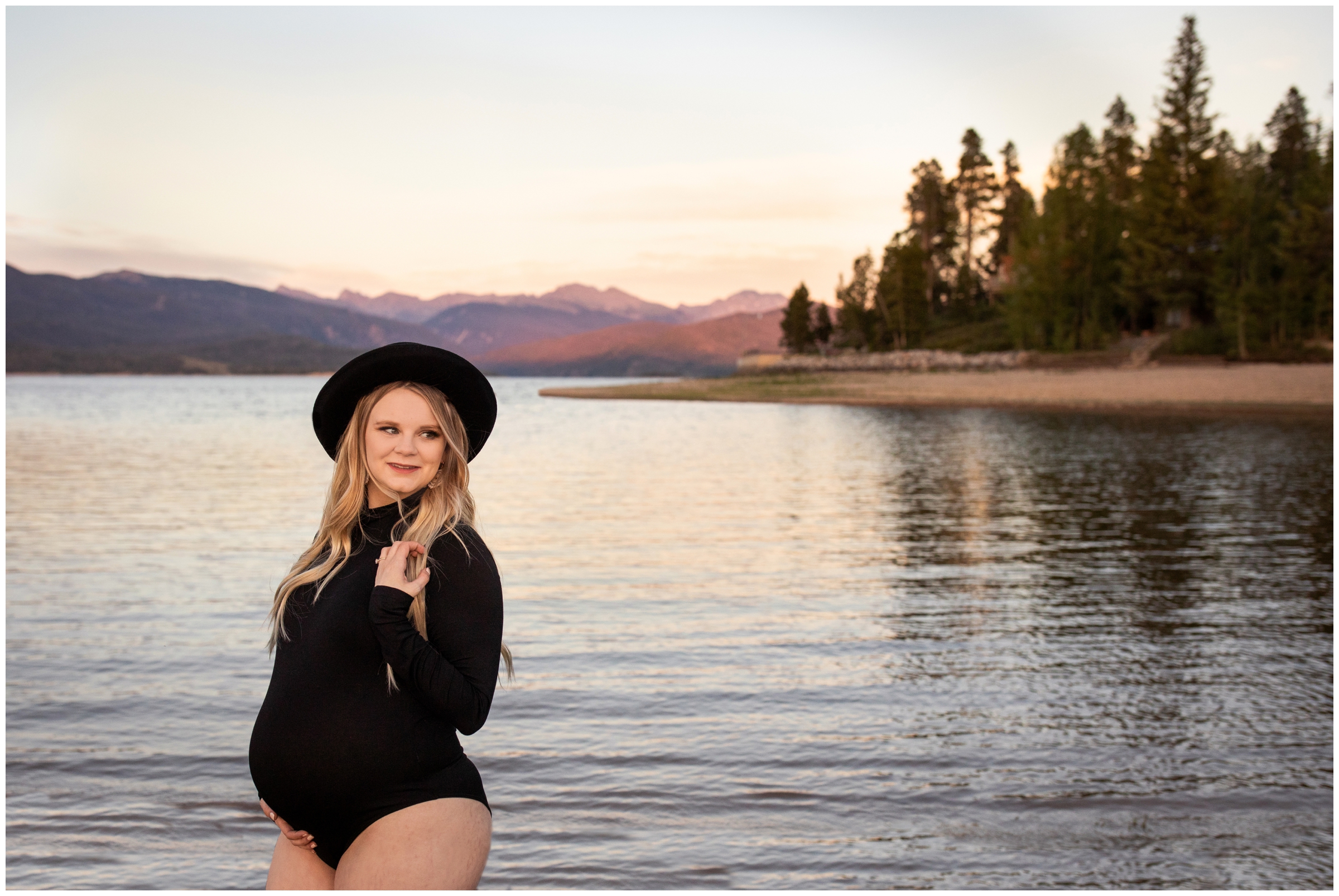 pregnant woman posing in bodysuit and hat during Colorado lake maternity photography session