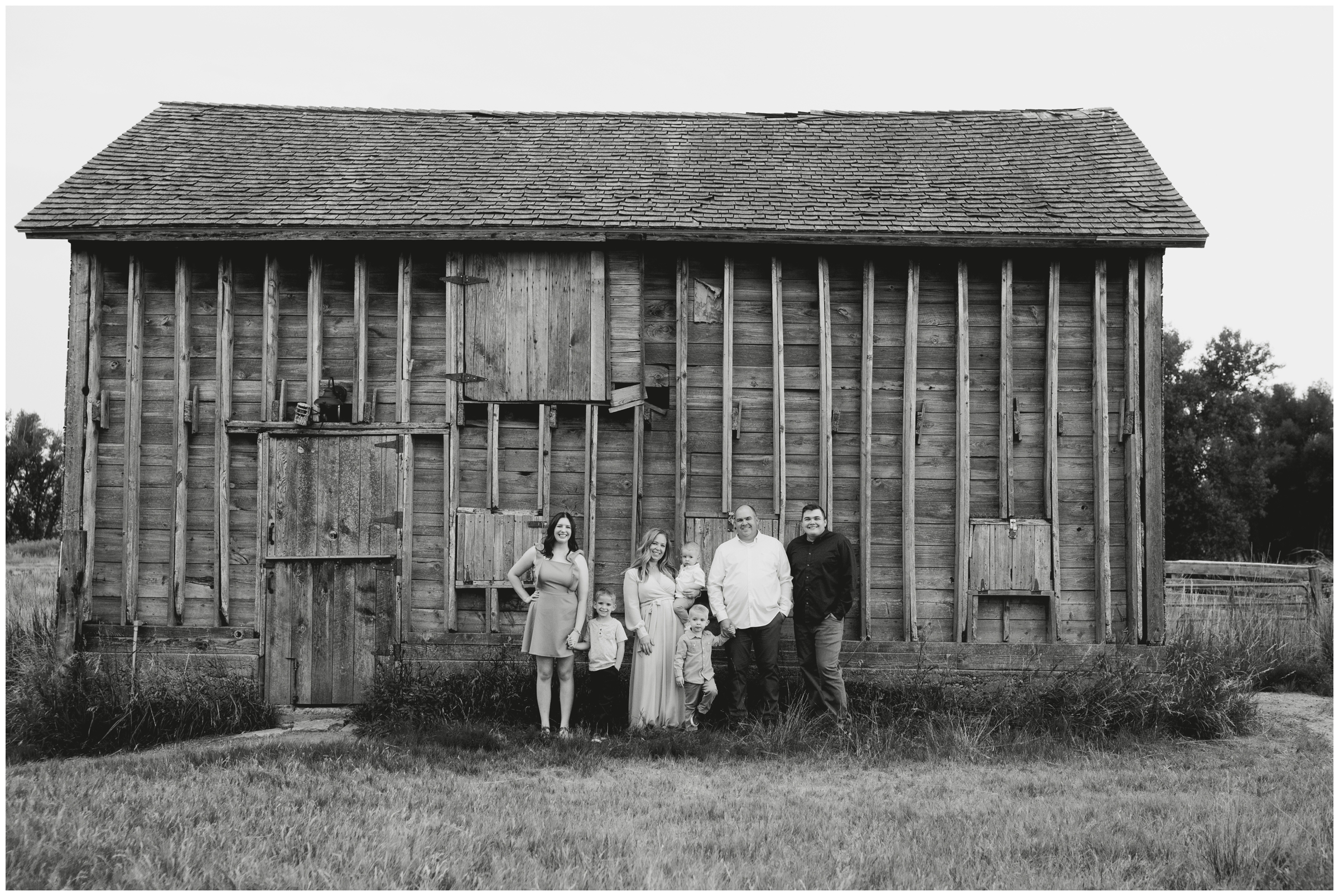 family of seven posing in front of rustic wooden bridge during Sandstone Ranch Longmont family photos 