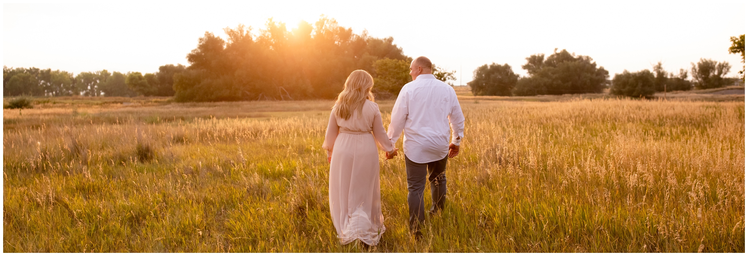 parents walking through golden field during family photography session in Longmont Colorado 