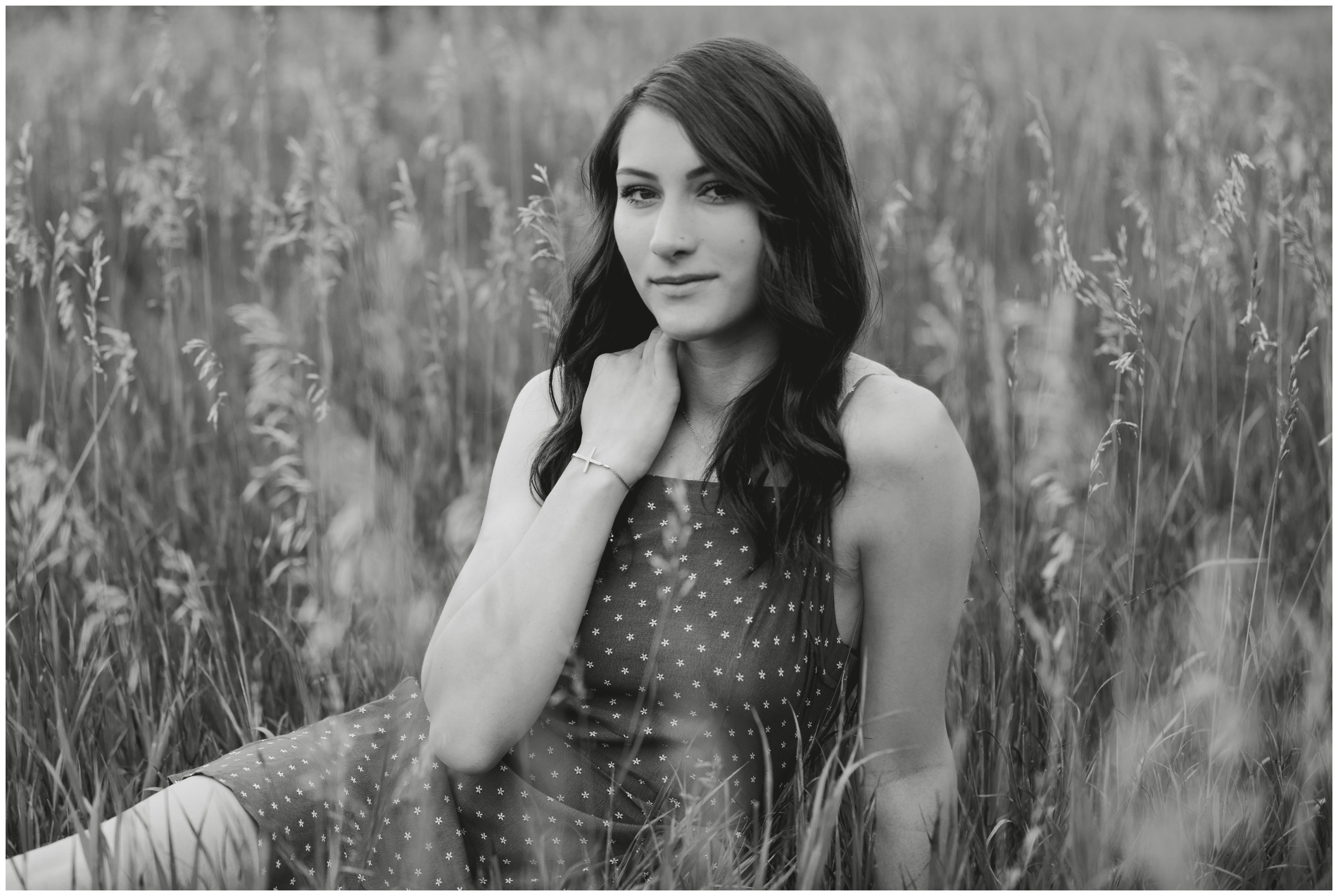 black and white photo of teen sitting in a field during Colorado senior photos 