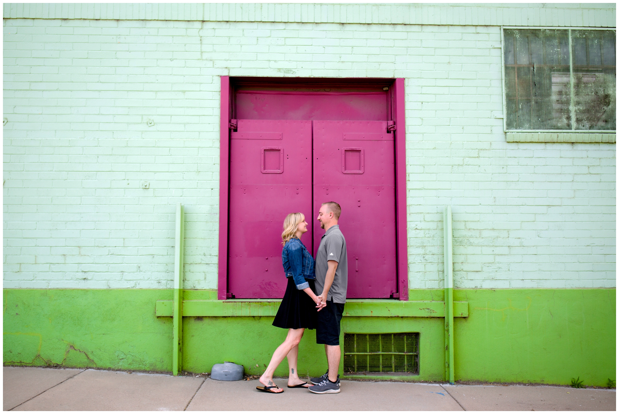 couple holding hands in front of colorful wall at Denver engagement photos 