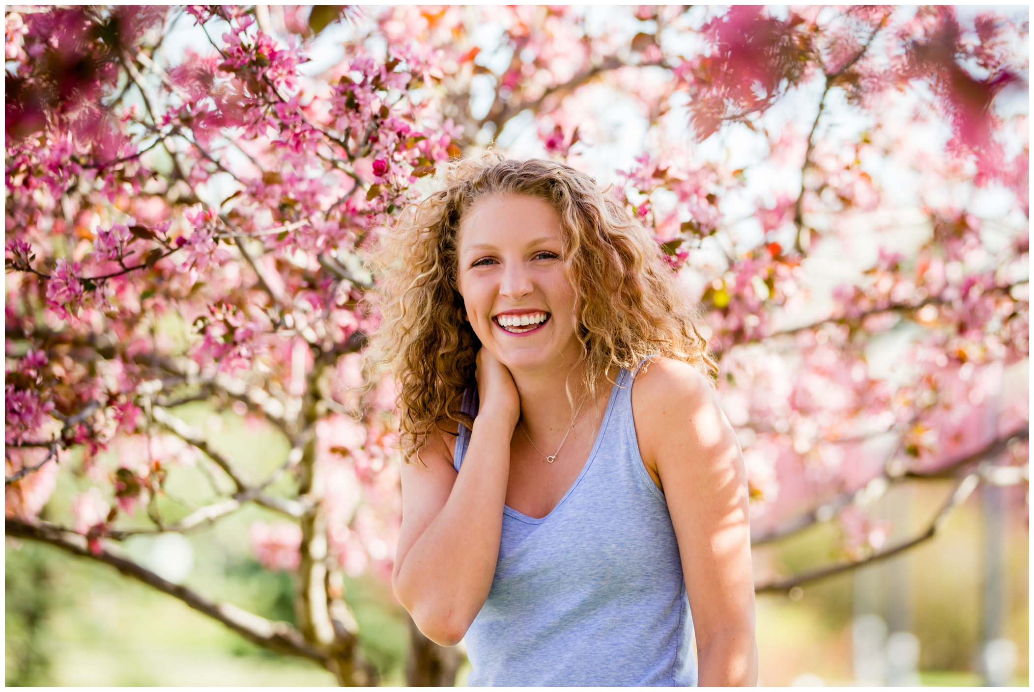 girl laughing in cherry blossoms during Mead High School senior photography session 