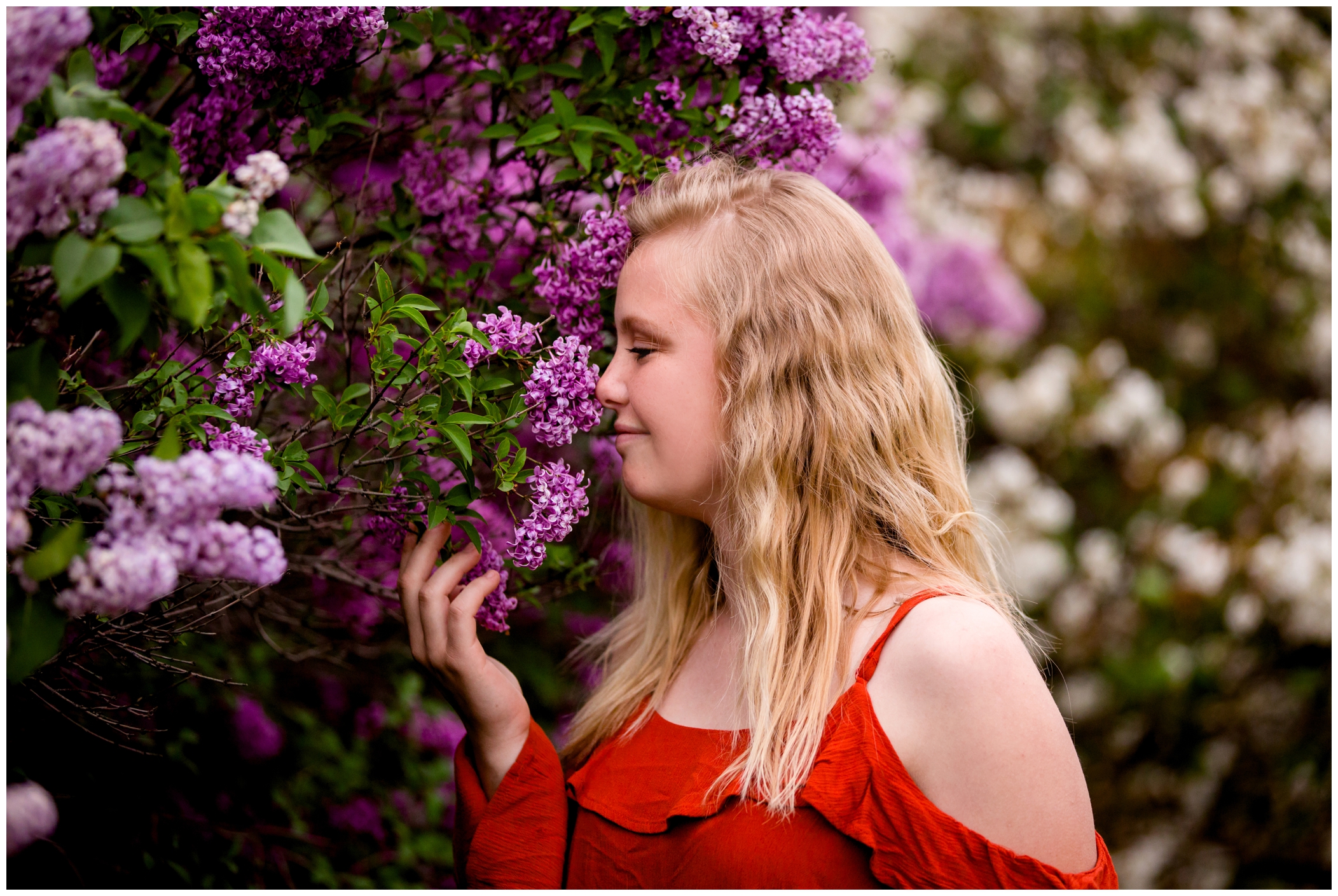 teen girl smelling lilac flowers during longmont high senior portraits in Colorado 