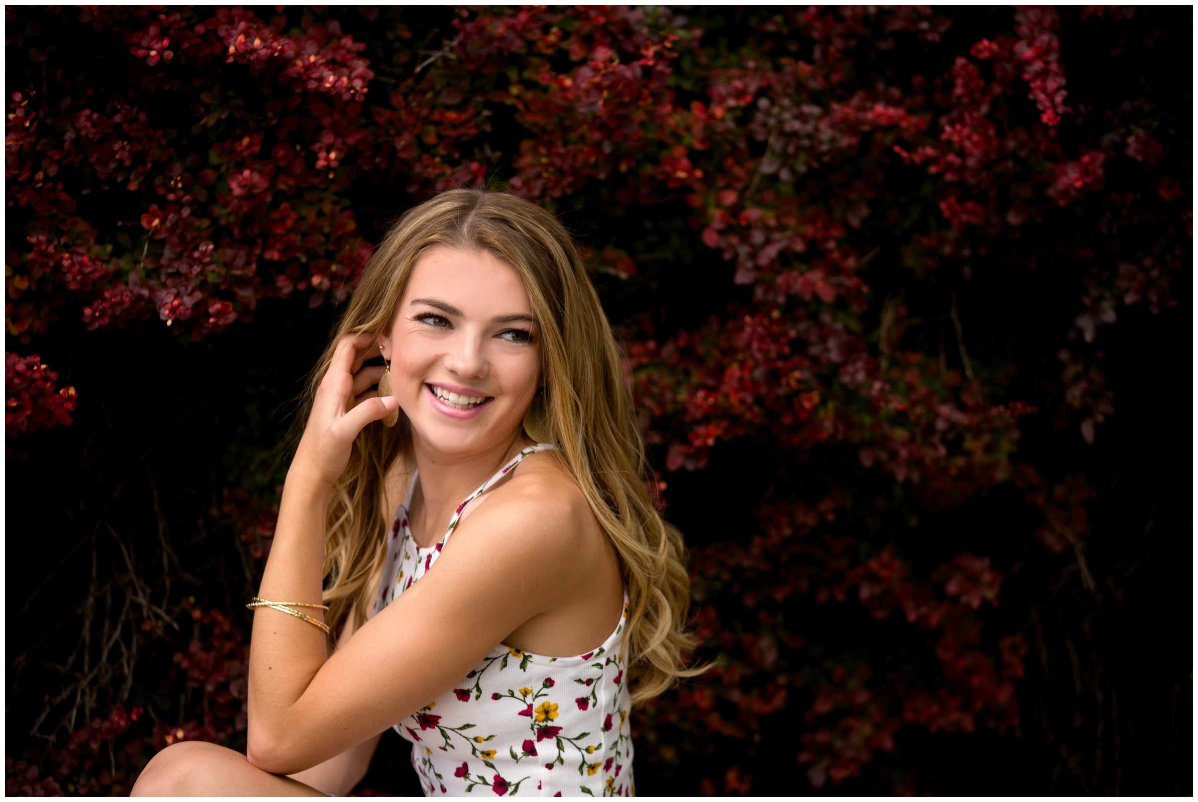 Frederick High School student posing in front of red flowers at urban Colorado senior photography session 