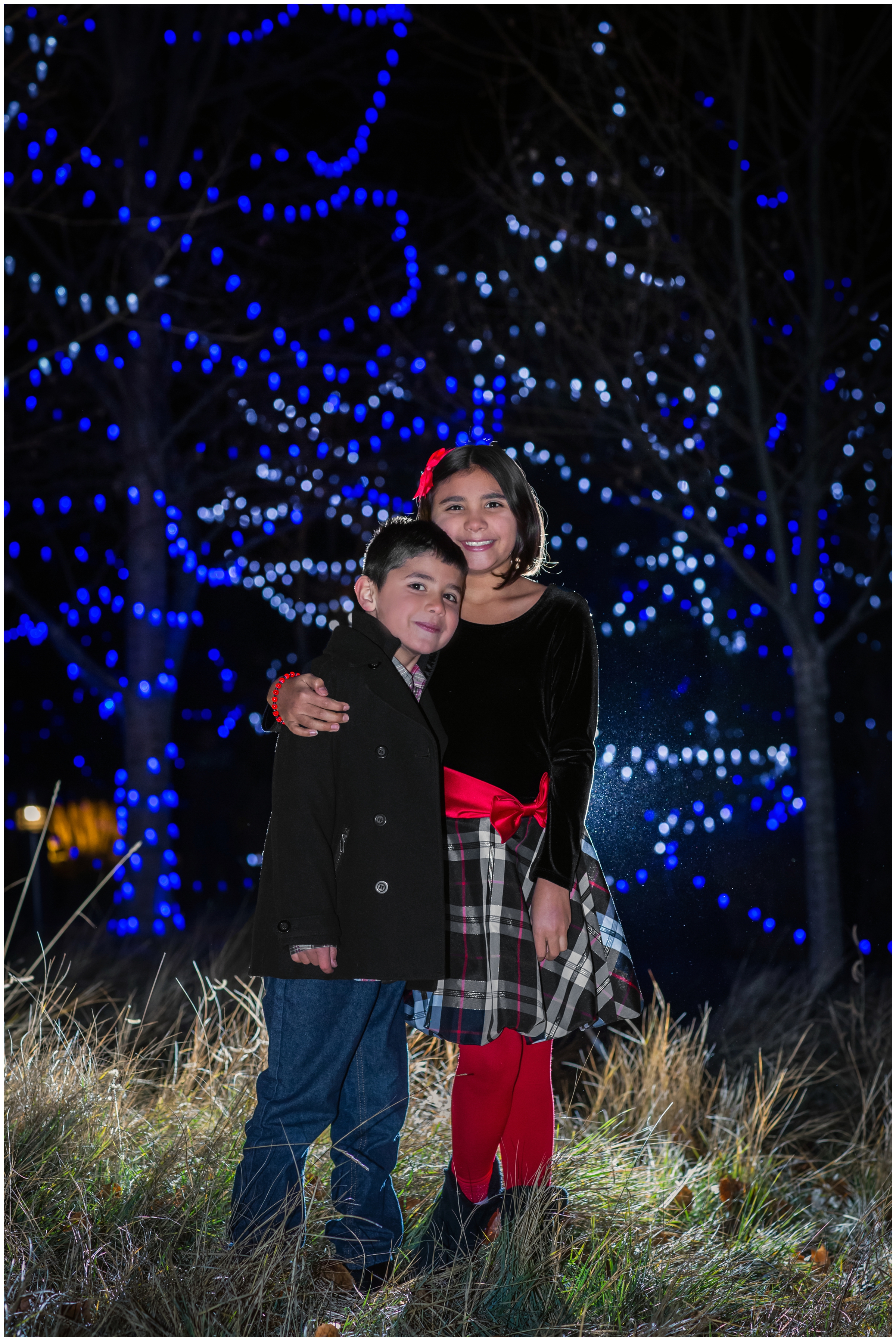 brother and sister hugging at Loveland Colorado family pictures at Winter Wonderlights at Chapungu Sculpture Garden