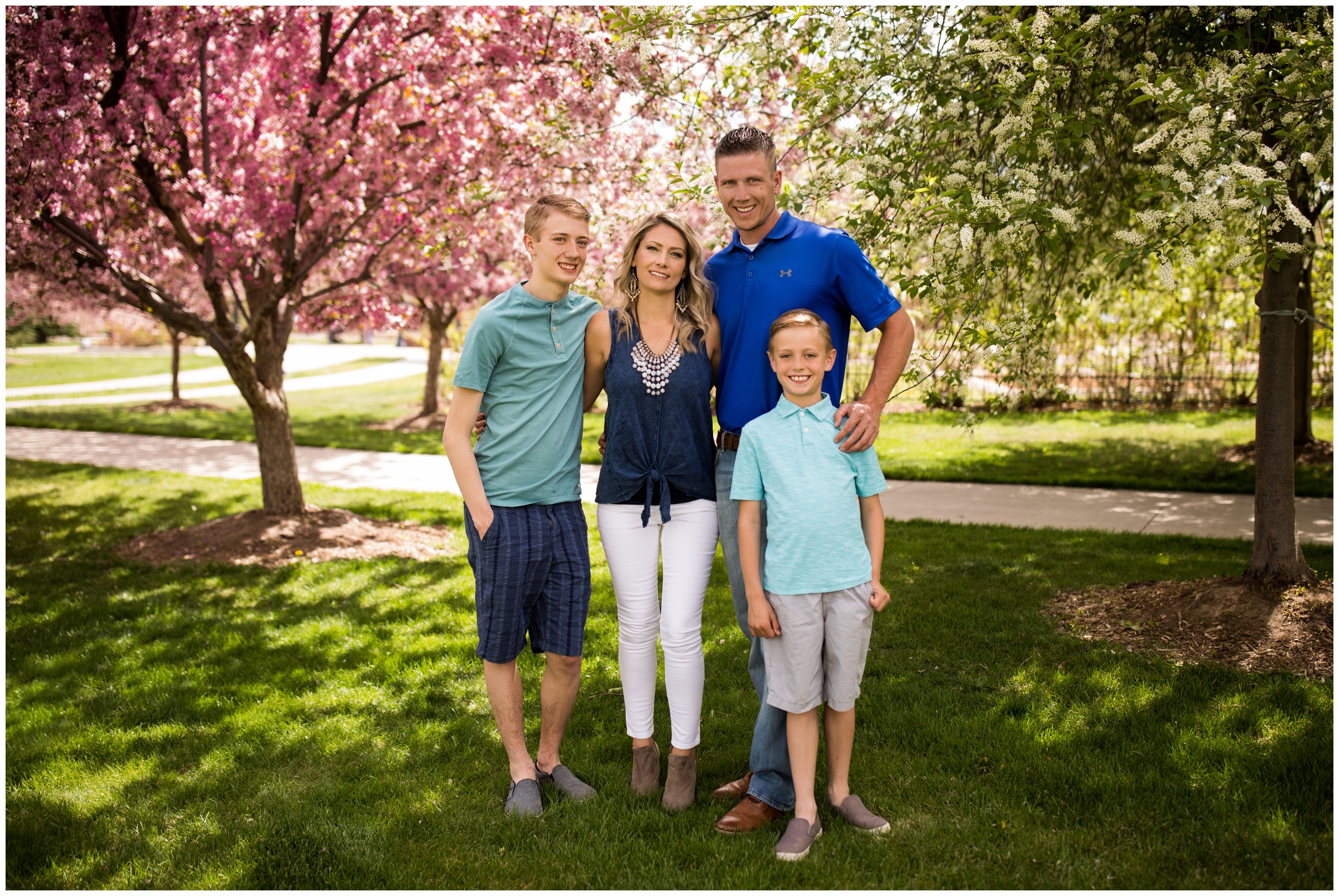 family standing under cherry blossom trees during spring family photography session in Longmont Colorado 