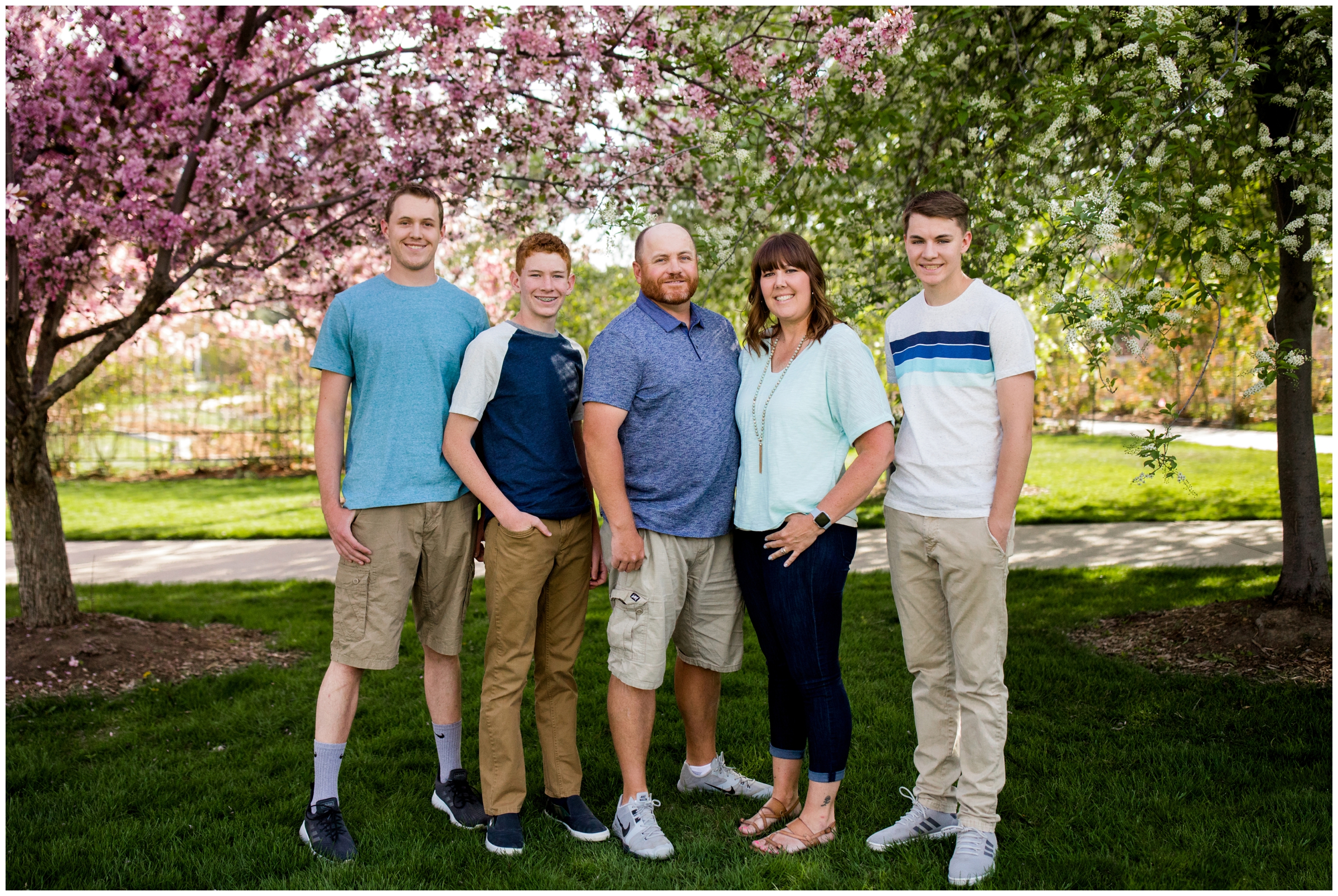 family standing under cherry blossom trees during spring Longmont family photography session