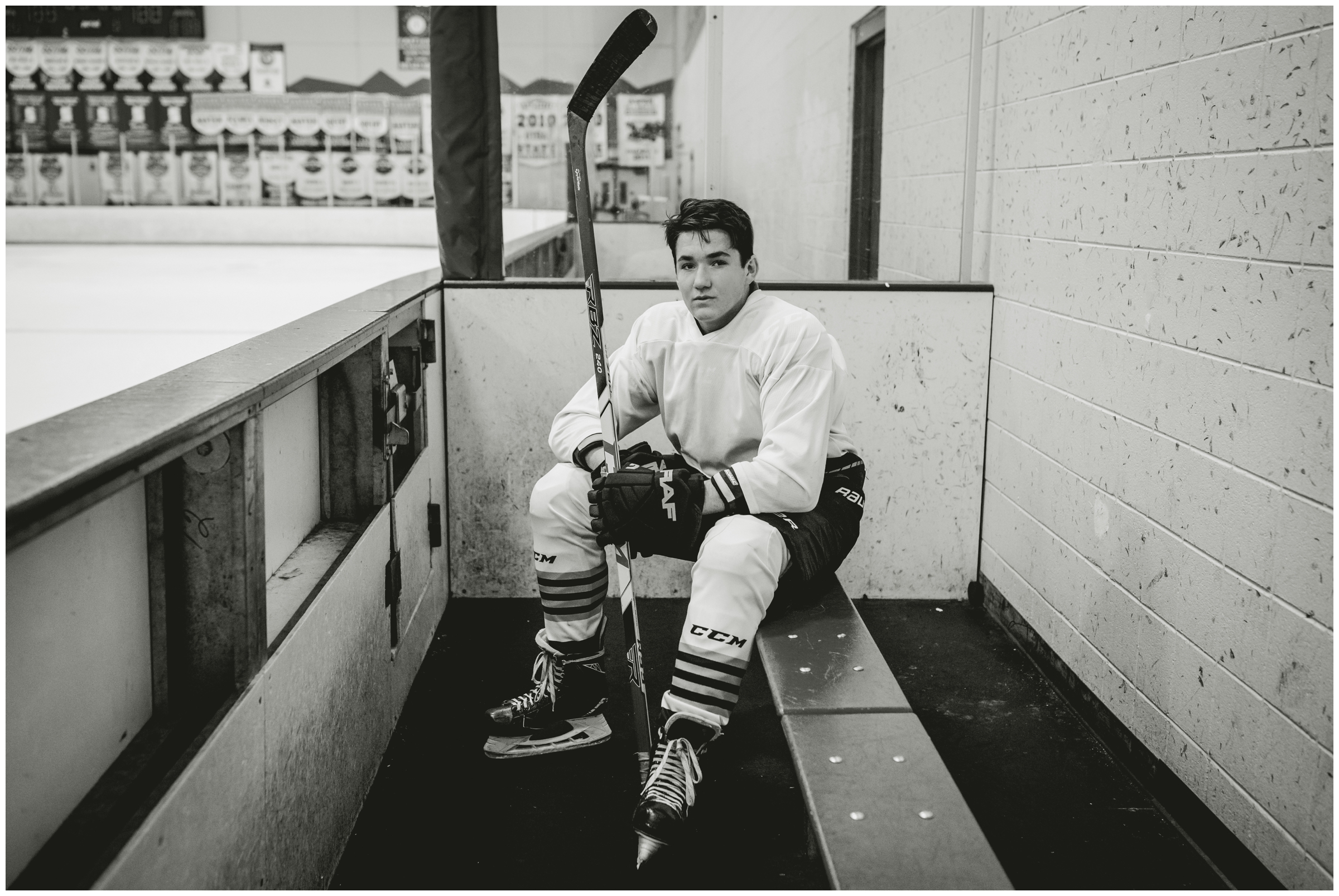 hockey player sitting on bench at APEX center during Colorado hockey senior photos