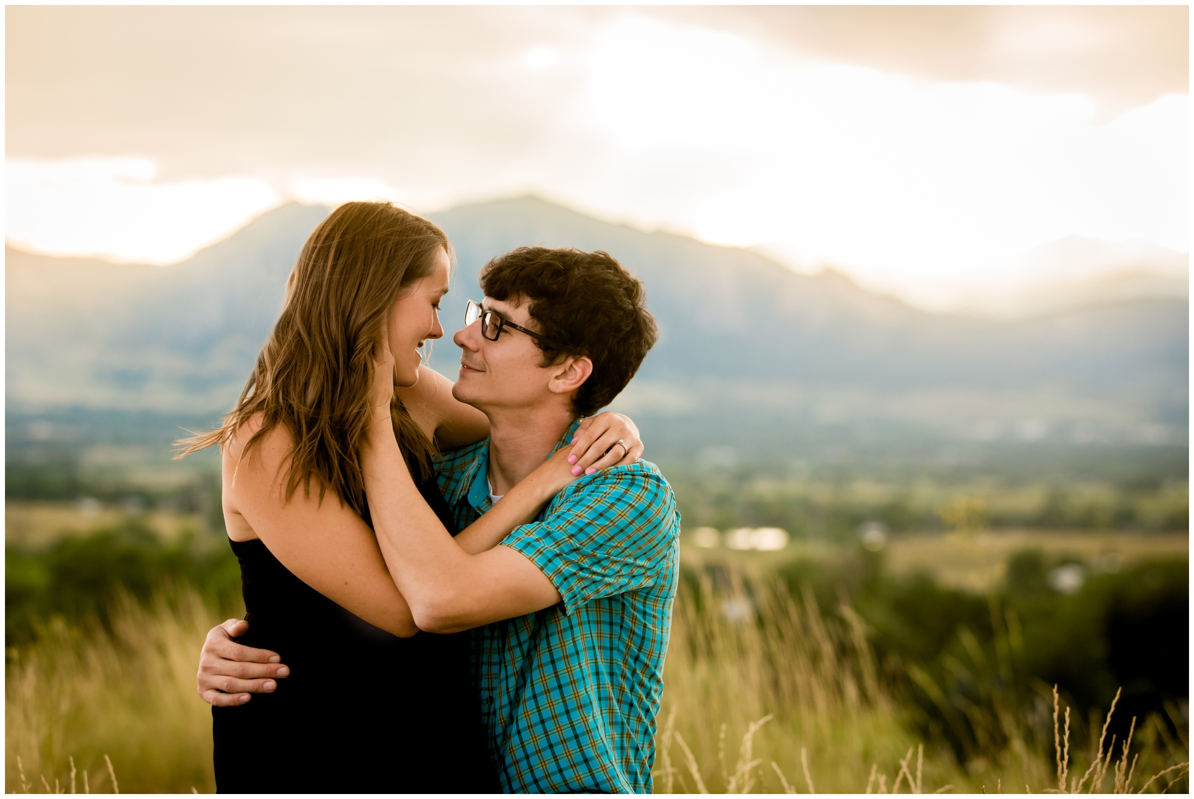 couple embracing with flatirons in background during Colorado engagement pictures