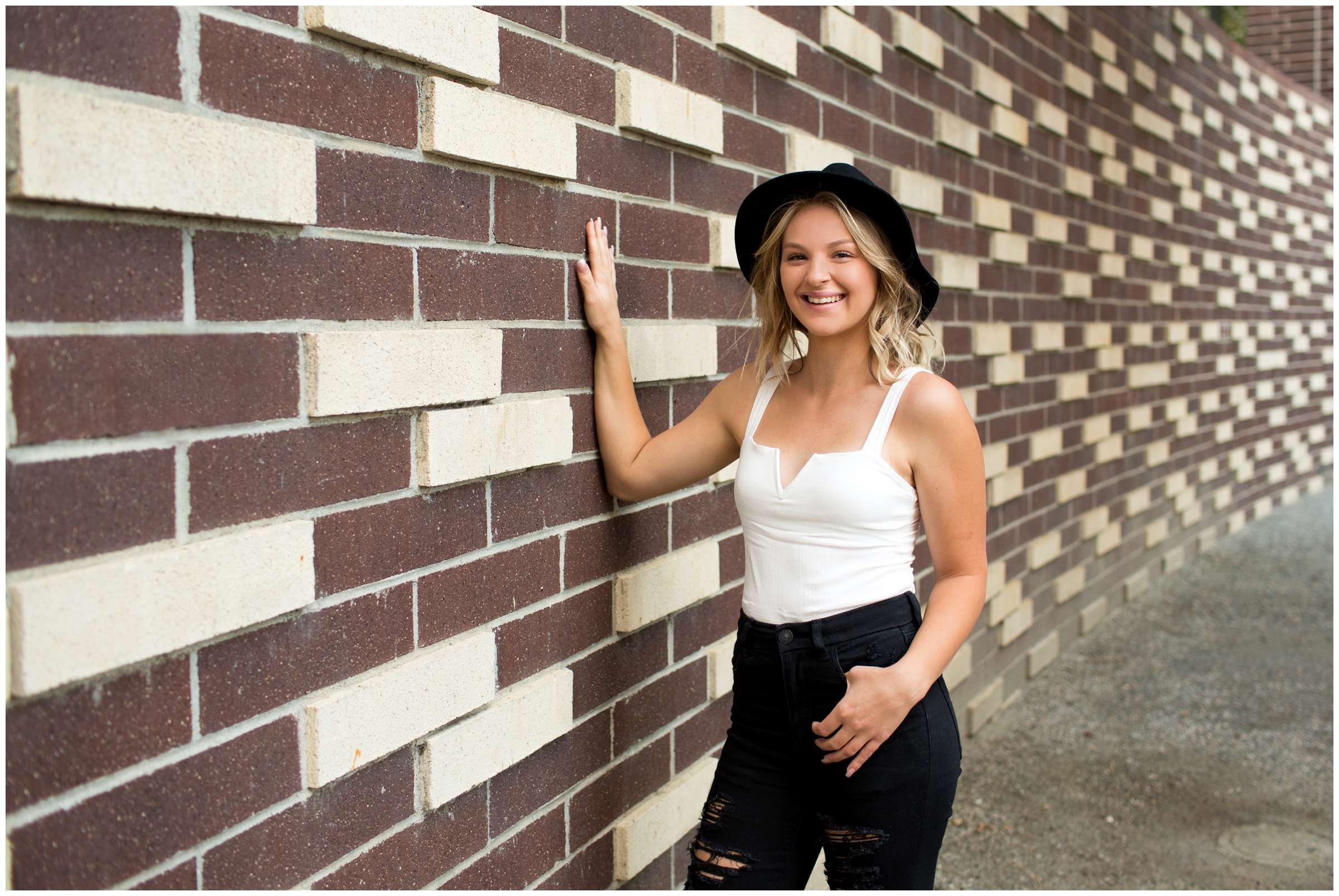 teen posing next to brick wall at Denver senior photography session 