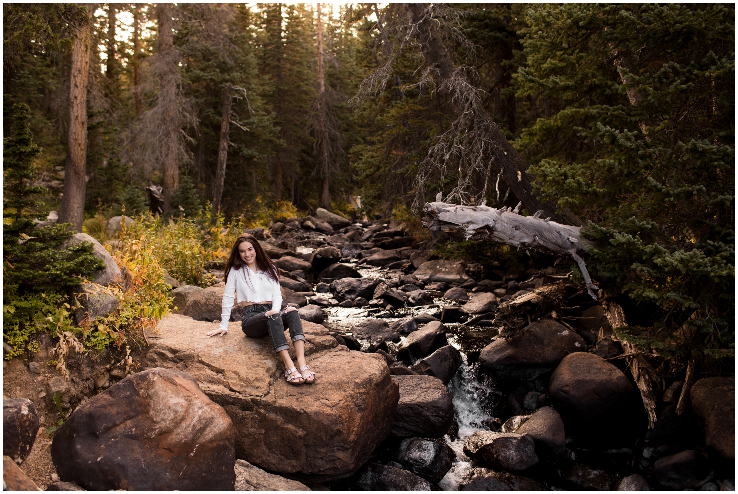 teen posing by mountain waterfall during Colorado fall senior pictures 