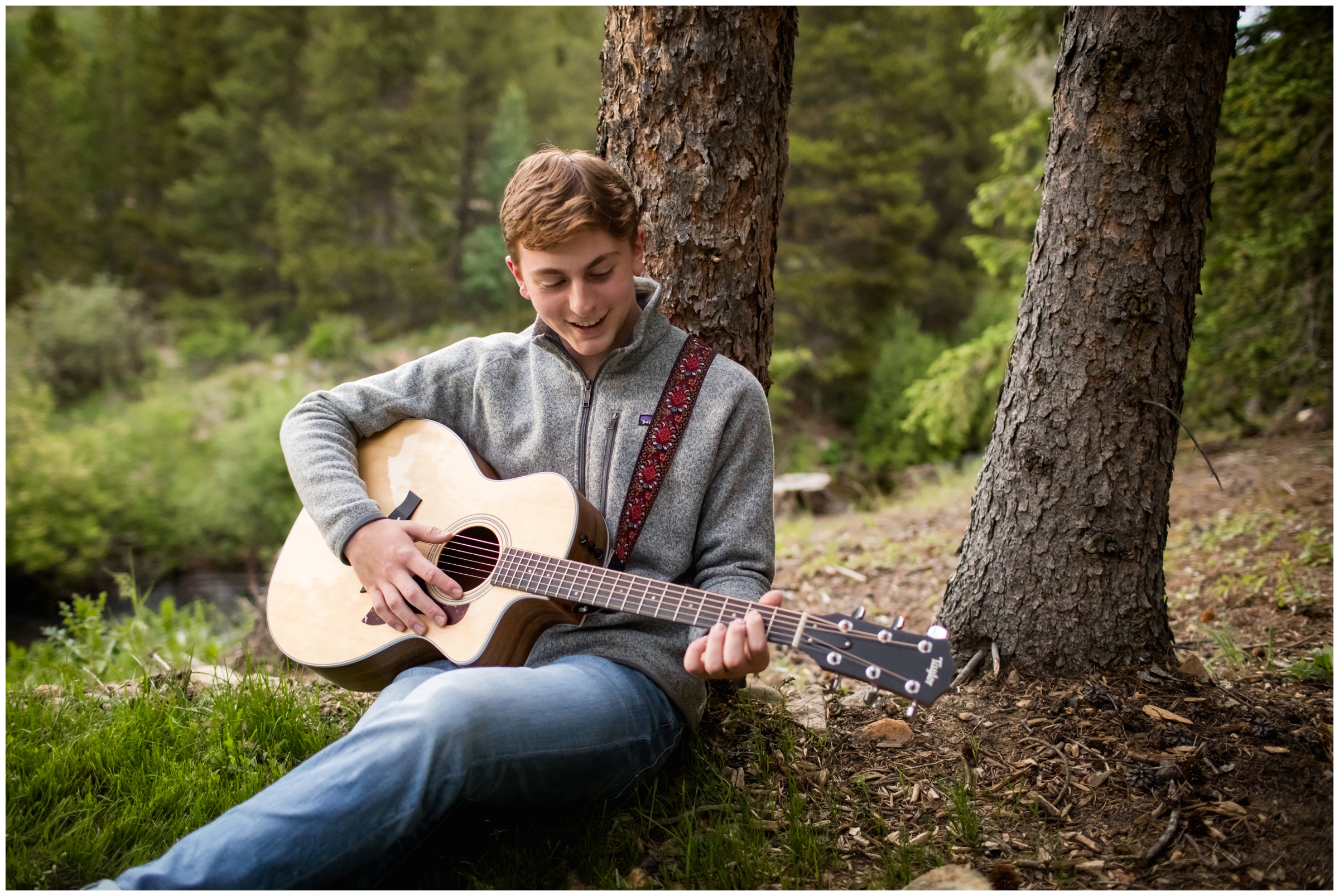 teen guy playing guitar in the mountains during Boulder Colorado forest senior photos