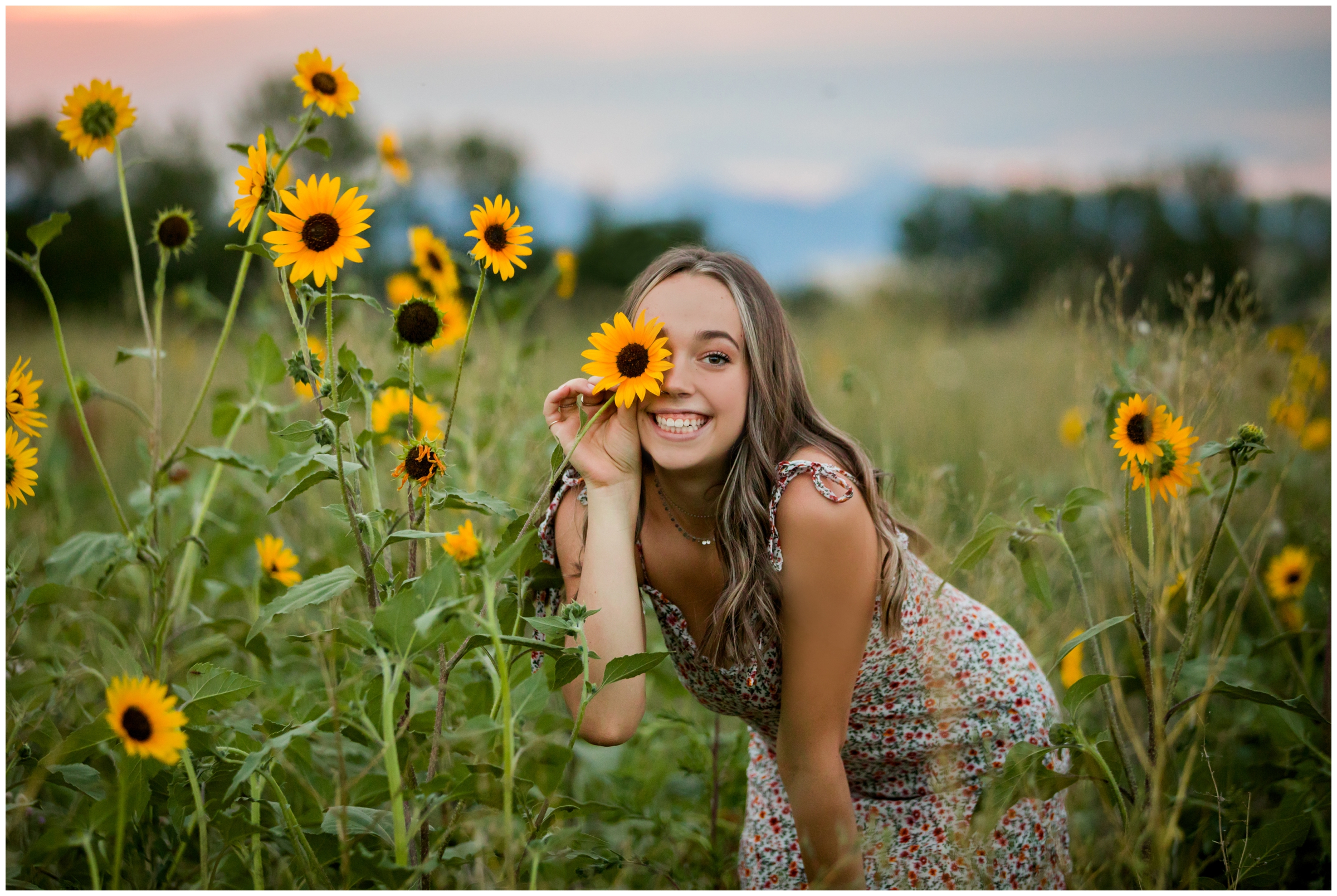 teen holding sunflower over eye during Skyline High senior photos in Longmont Colorado 
