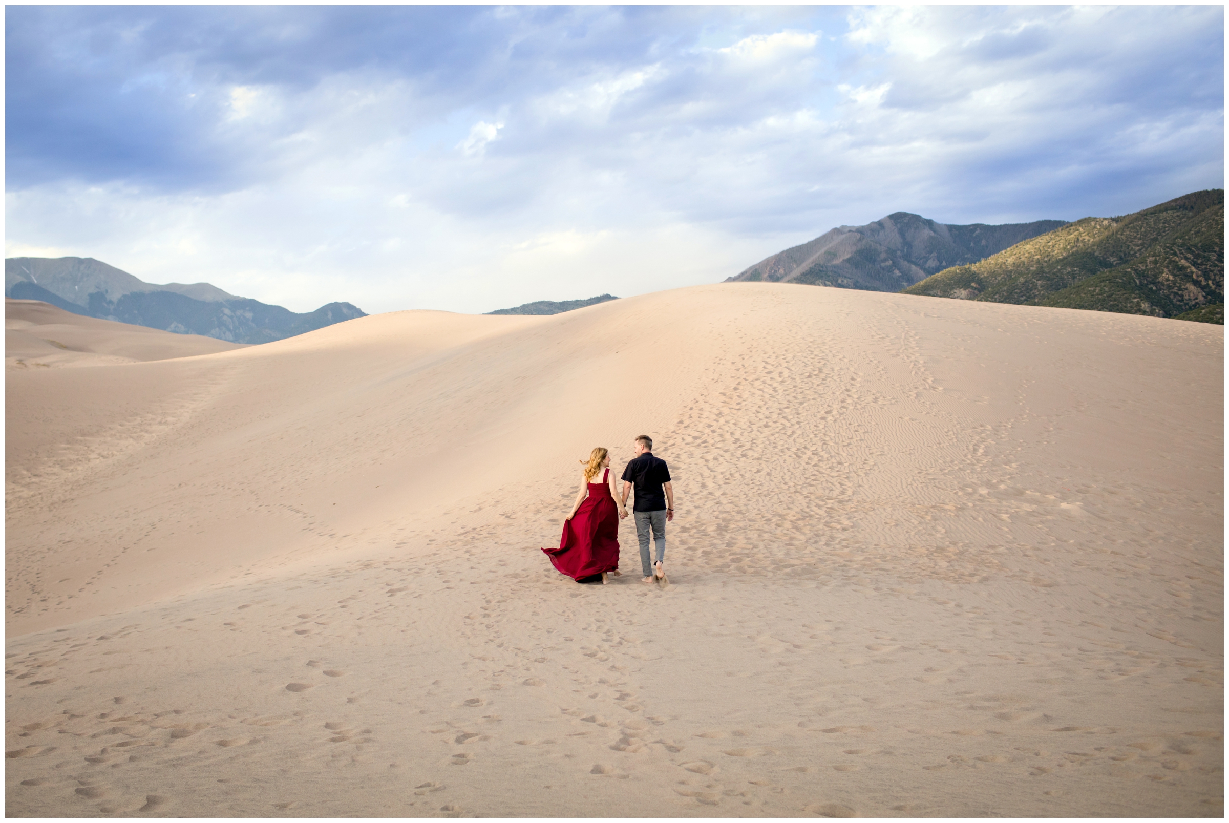 couple walking up the large dunes of Great Sand Dunes National Park during Colorado couples portraits 