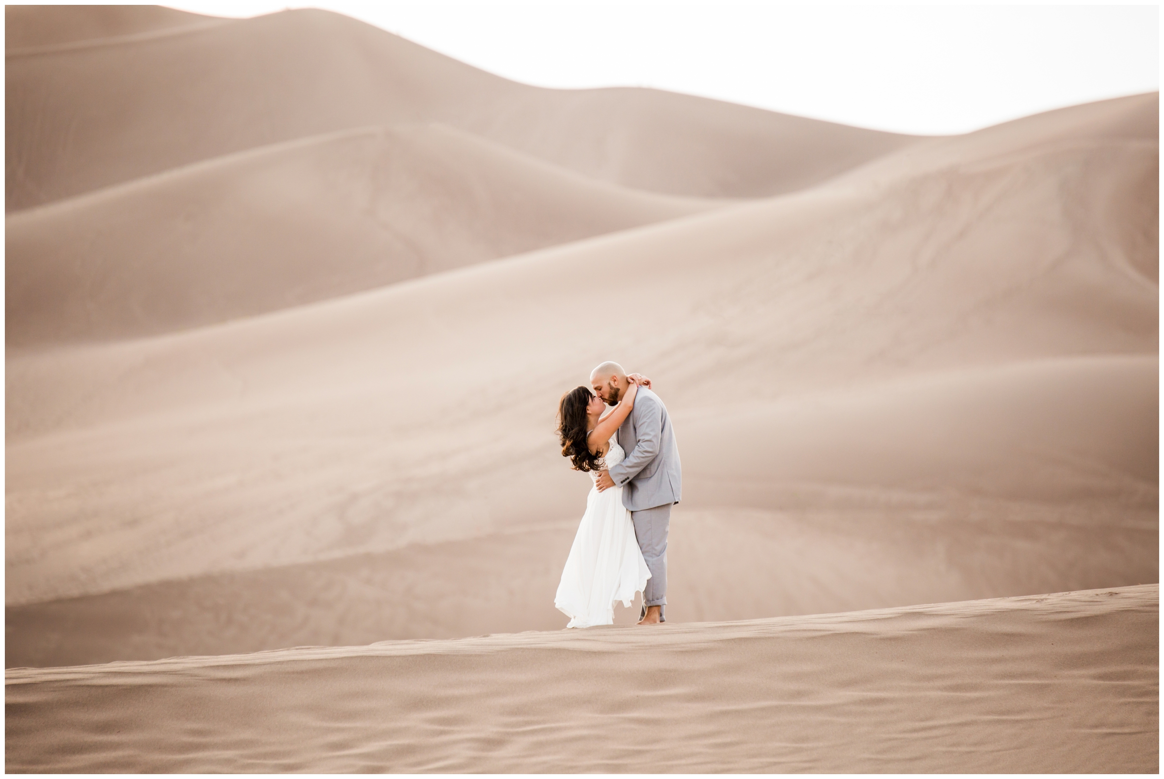 couple embracing during Colorado sand dunes engagement photos by CO wedding photographer Plum Pretty Photography