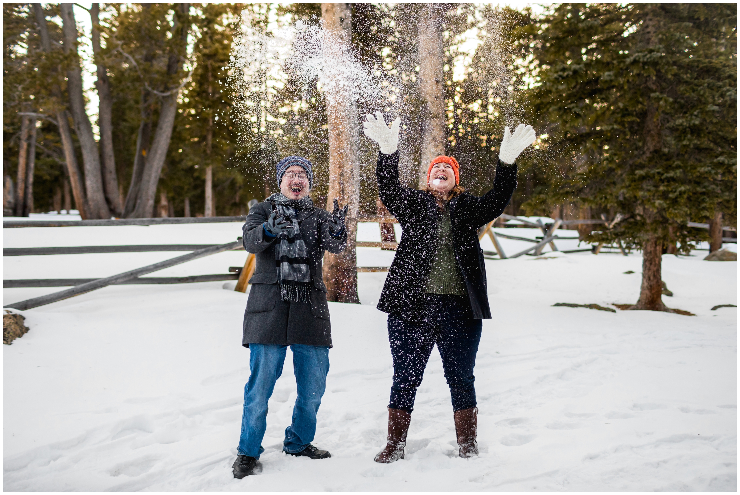 couple throwing snow in the air during Colorado winter engagement photos in Idaho Springs