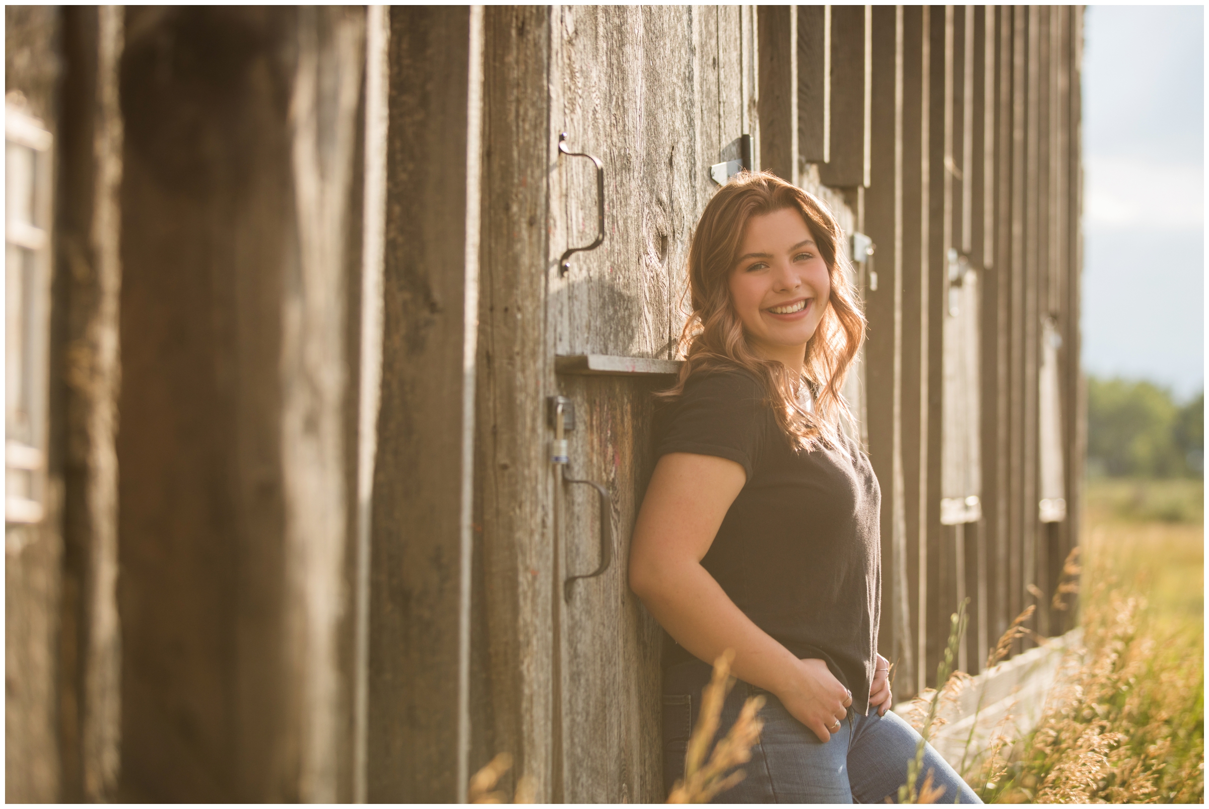 teen girl leaning on barn during Longmont Colorado senior pictures 