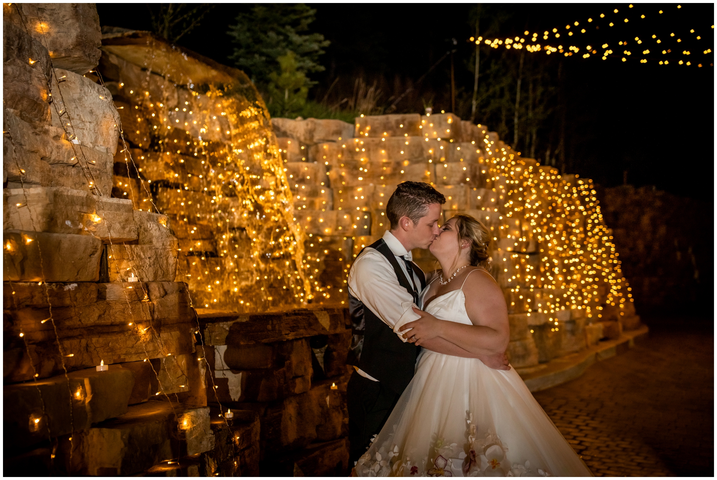 couple kissing under waterfall lights during Della Terra nighttime wedding photography 