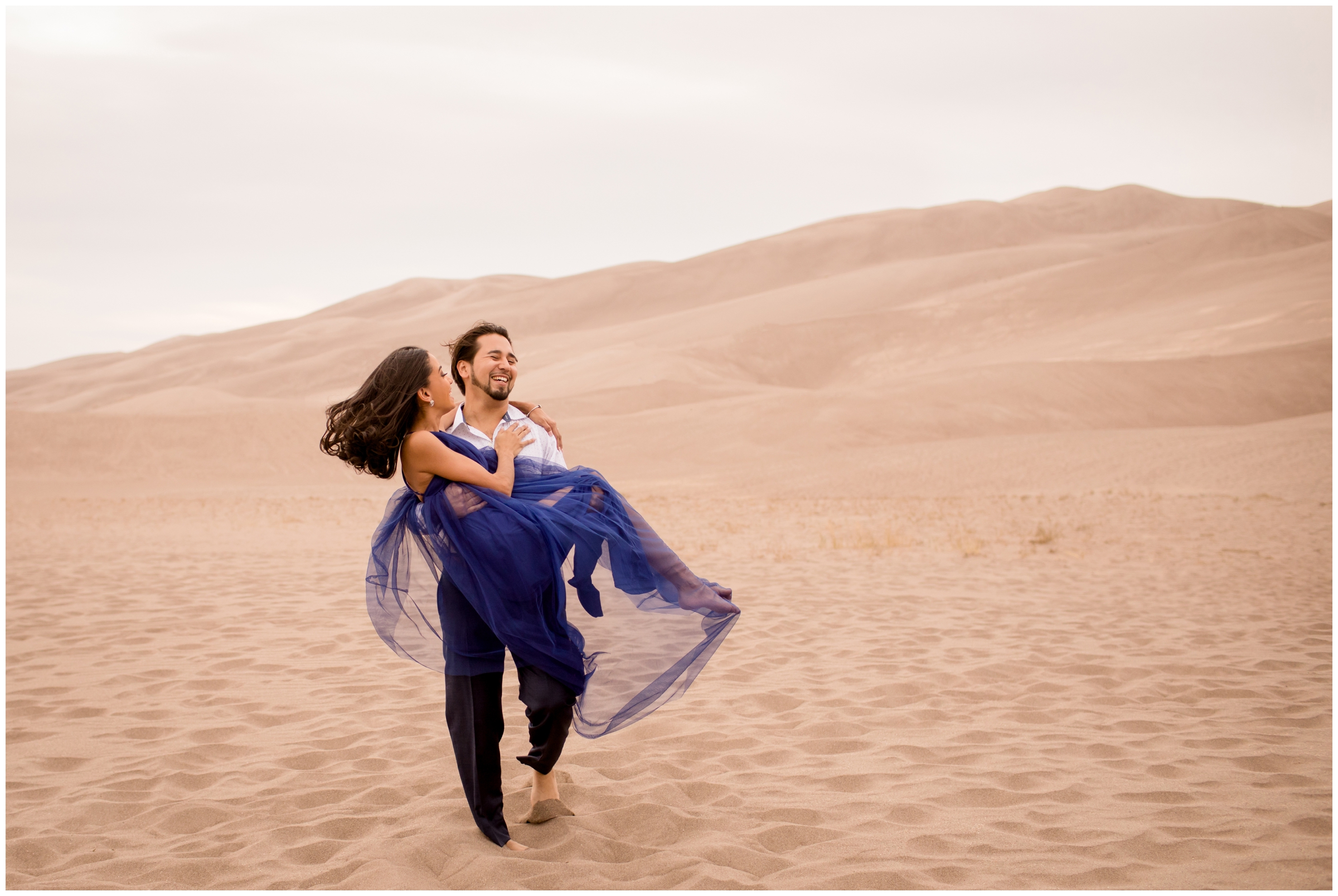 guy carrying fiancé during Sand Dunes Colorado engagement photos by CO wedding photographer Plum Pretty Photography