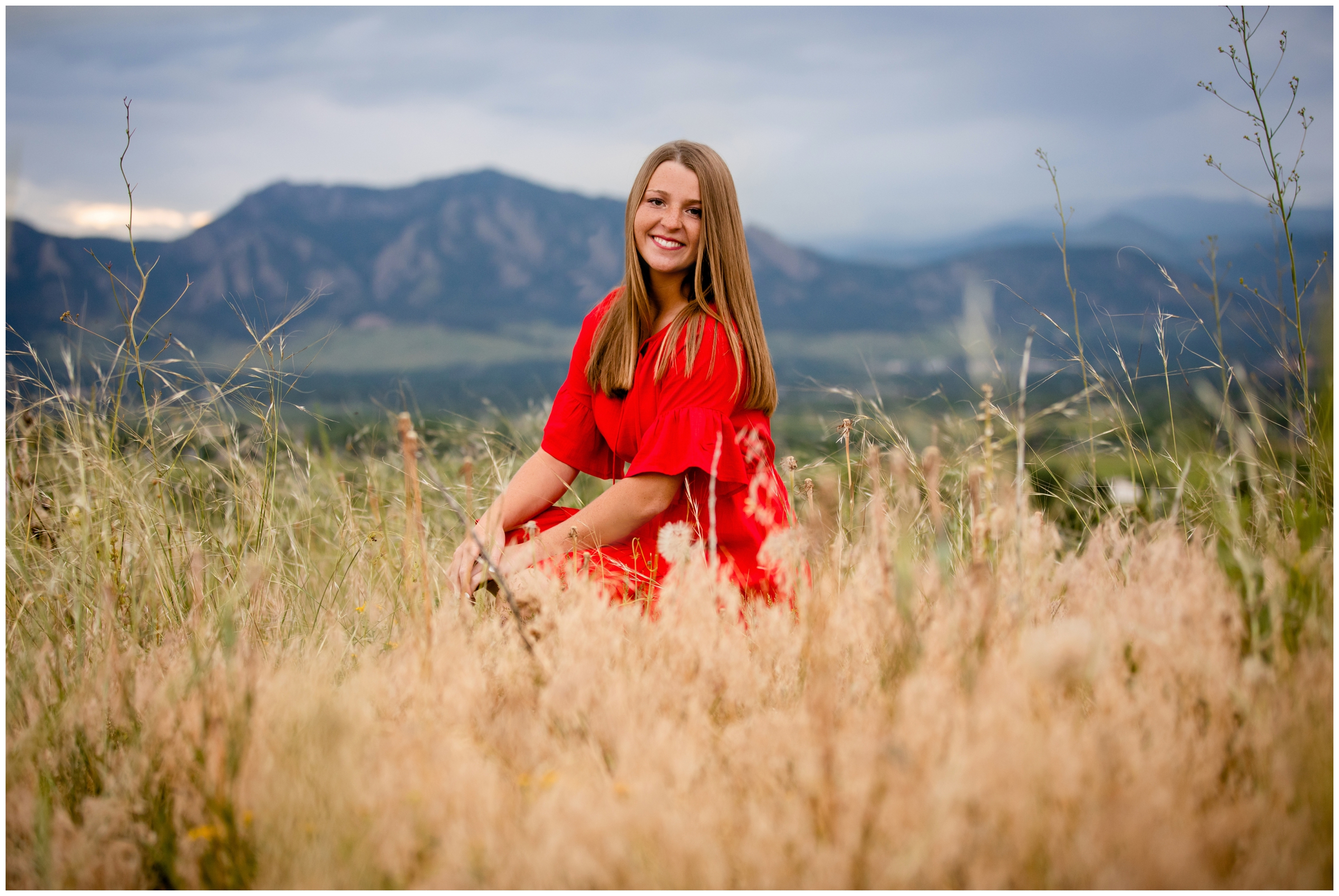 Teen girl in red dress posing in front of flatirons during senior photos in Boulder Colorado 