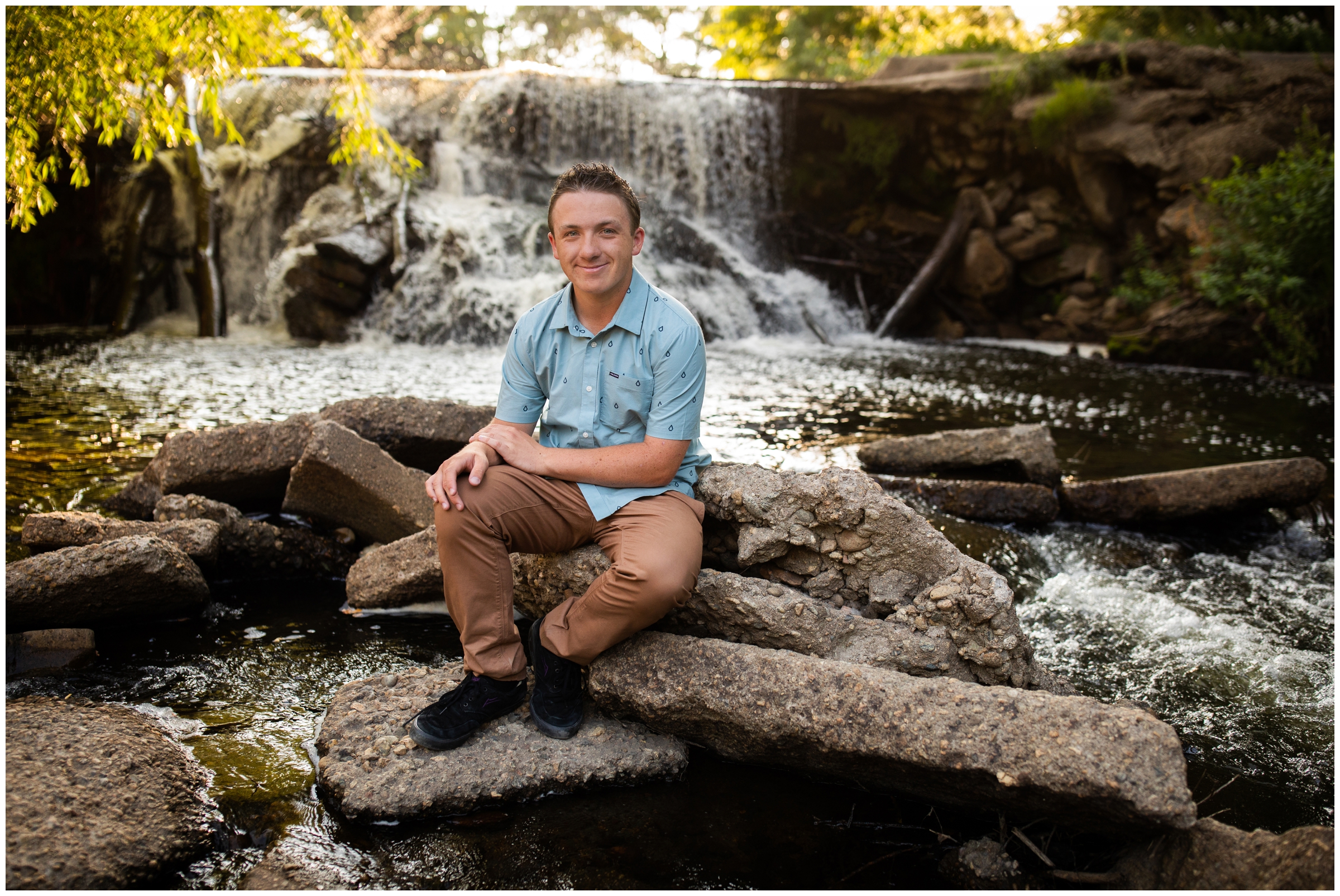 teen boy sitting by small waterfall during Golden Ponds Longmont senior pictures by Firestone Colorado portrait photographer Plum Pretty Photography