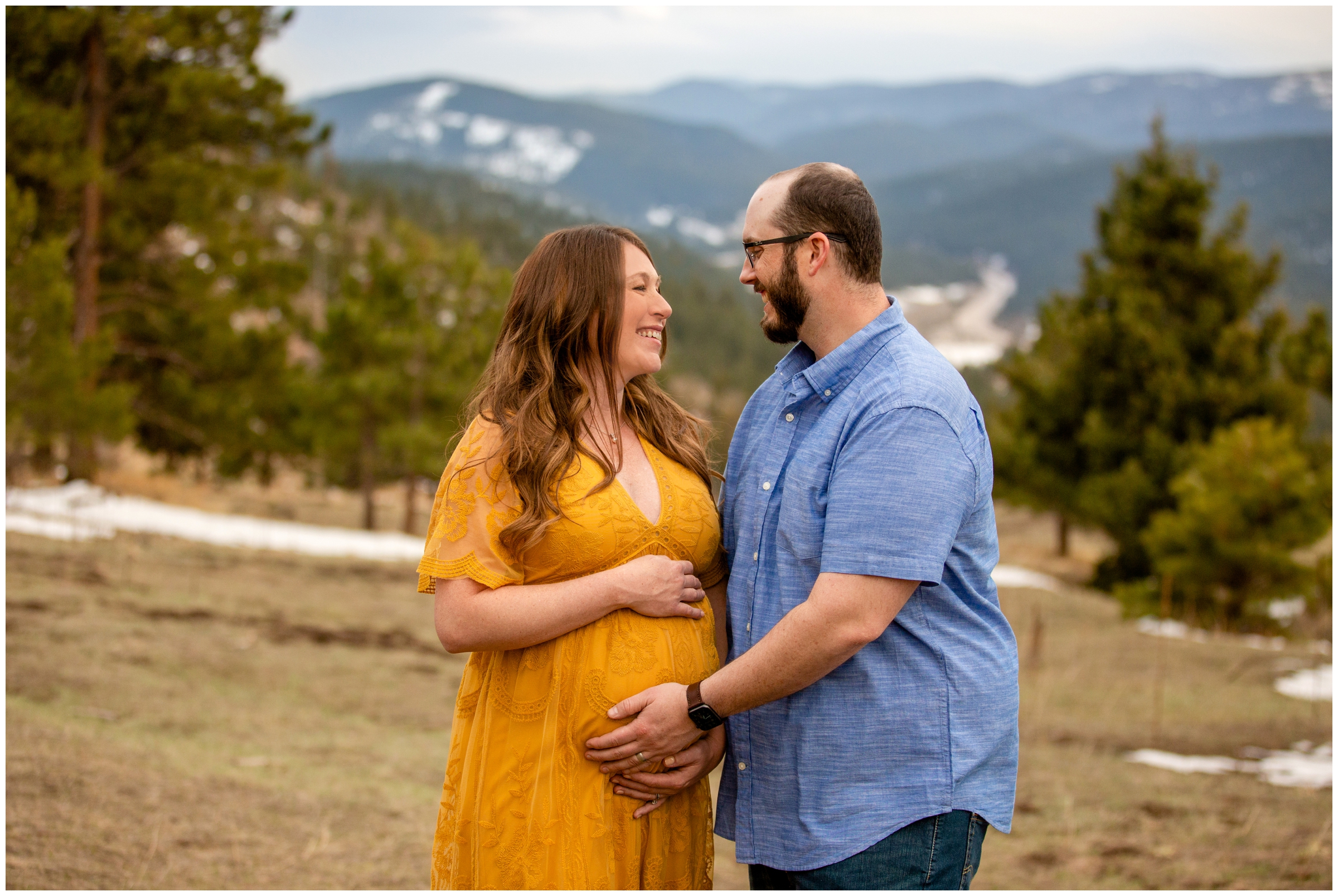 couple holding woman’s belly during Colorado mountain maternity pictures at mount falcon park