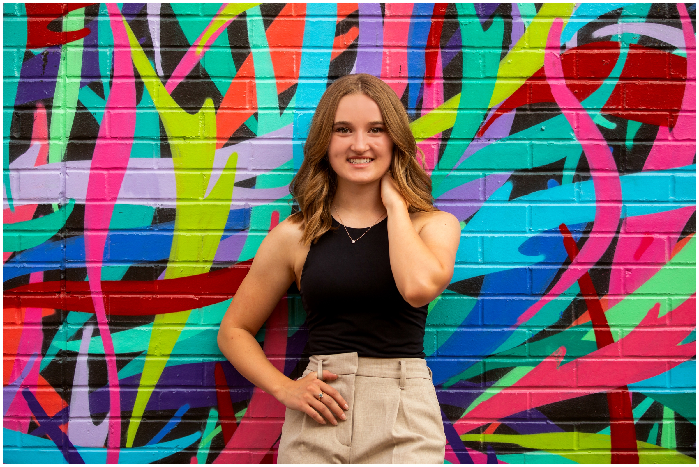 Teen posing in front of colorful wall mural during urban RINO Denver senior pictures by plum pretty photo