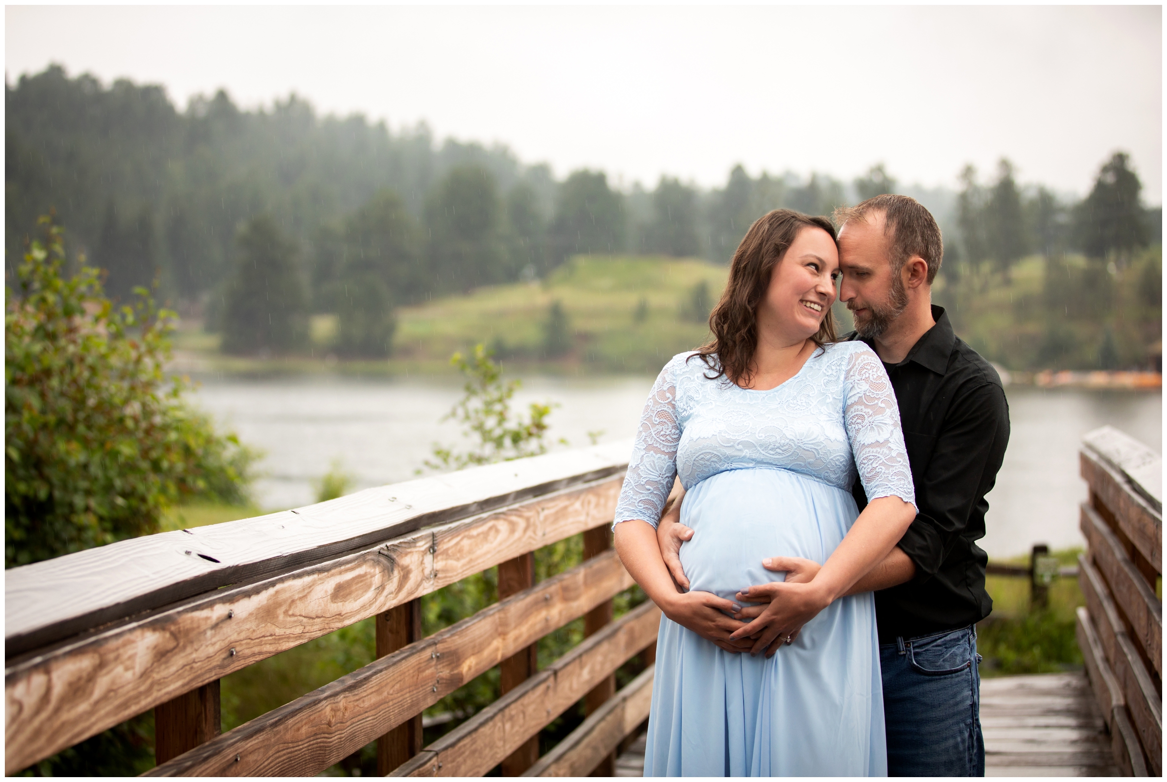 couple posing on a bridge in the rain during Evergreen Colorado maternity photos 