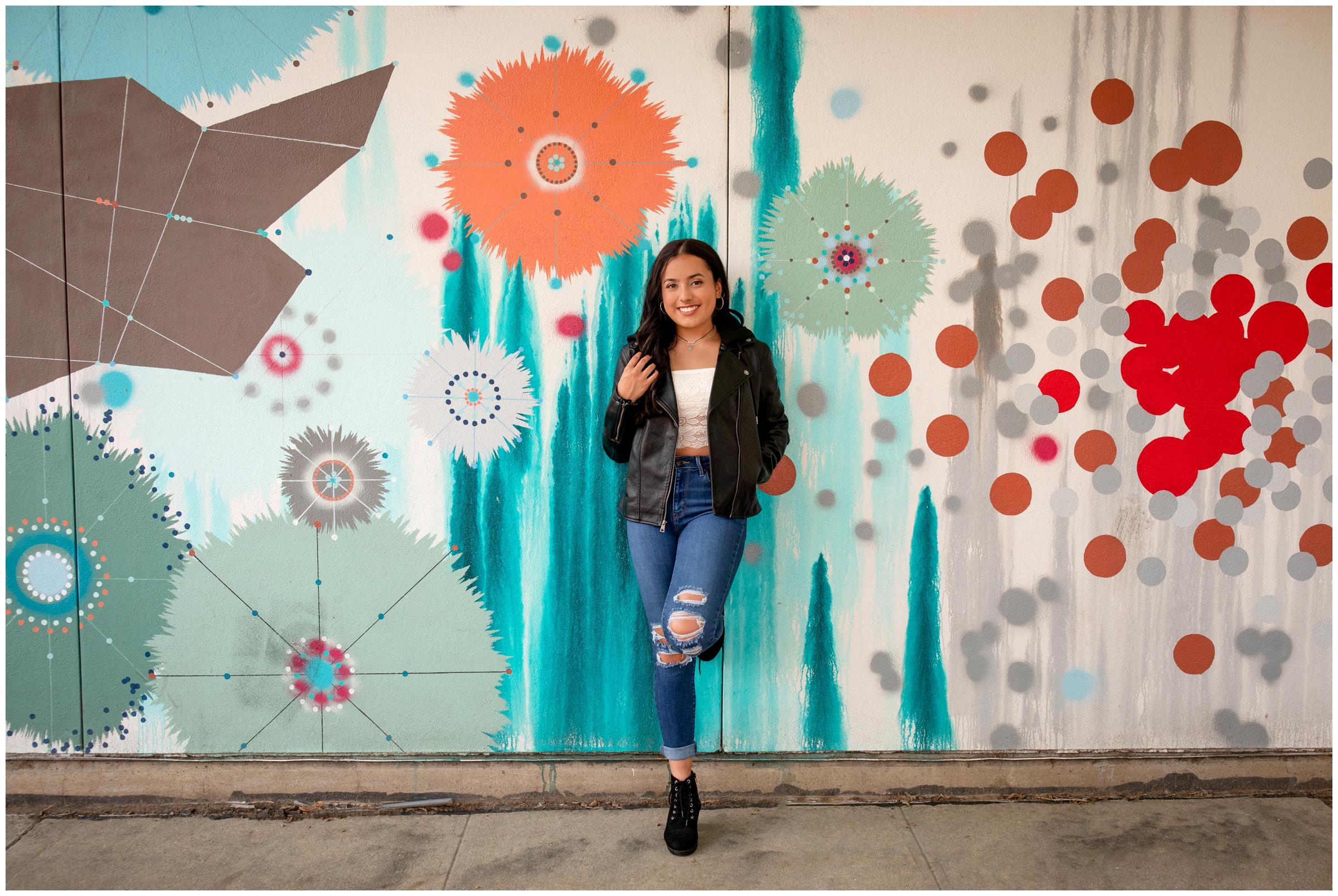 teen girl leaning against colorful mural wall during urban Colorado senior pictures