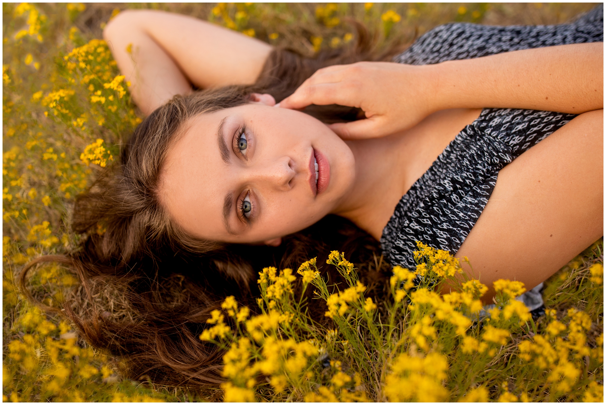 teen girl laying in field of yellow flowers during Colorado mountain senior photos