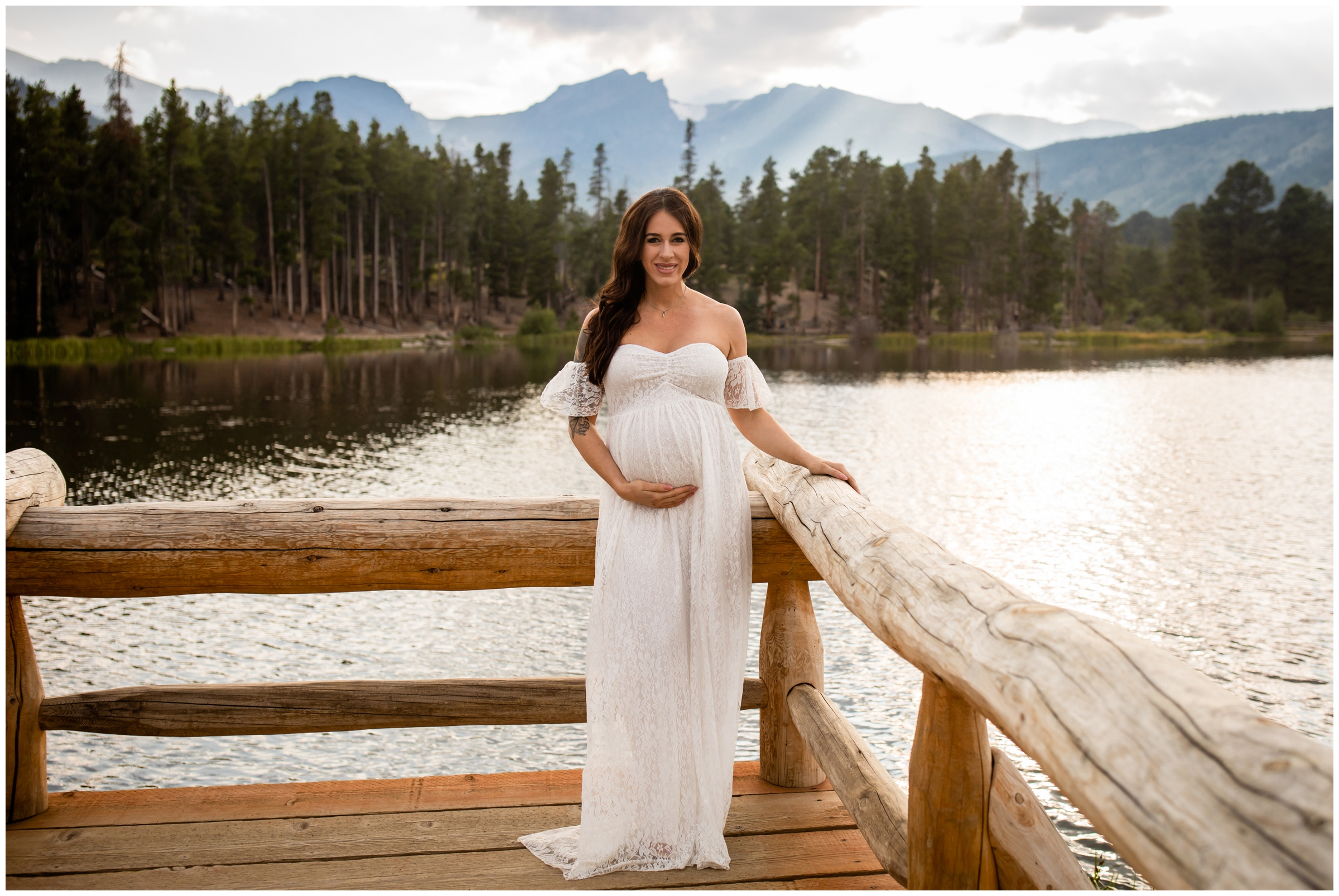 woman in white lace dress posing on a dock during Estes Park maternity portraits at Sprague Lake
