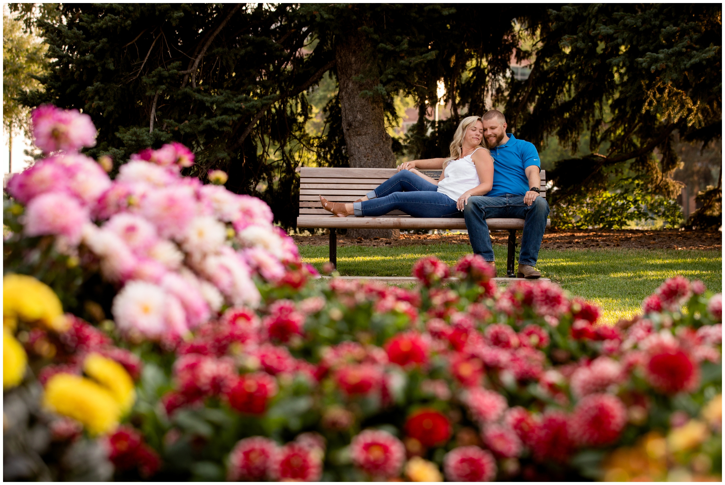 couple cuddling on a bench in a colorful flower garden during Fort Collins engagement portraits