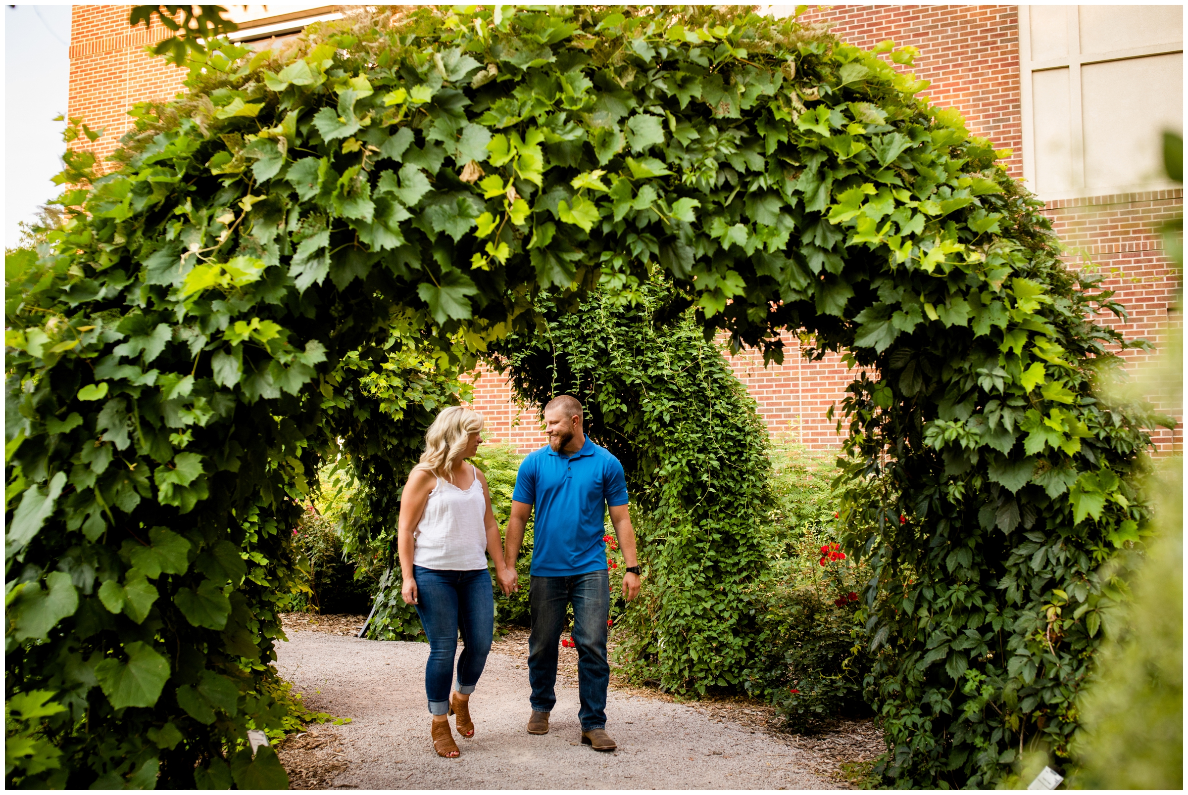 couple walking through greenery arch during Ft. Collins Colorado engagement pictures 